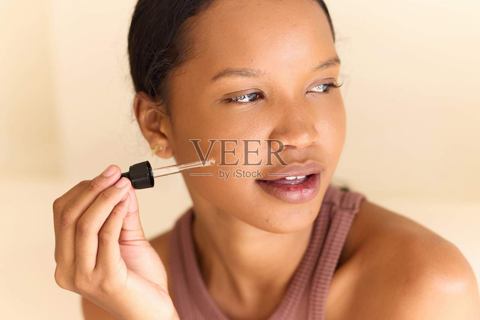 女性在护肤程序中涂抹面部精华液，以获得光滑健康的肌肤照片摄影图片