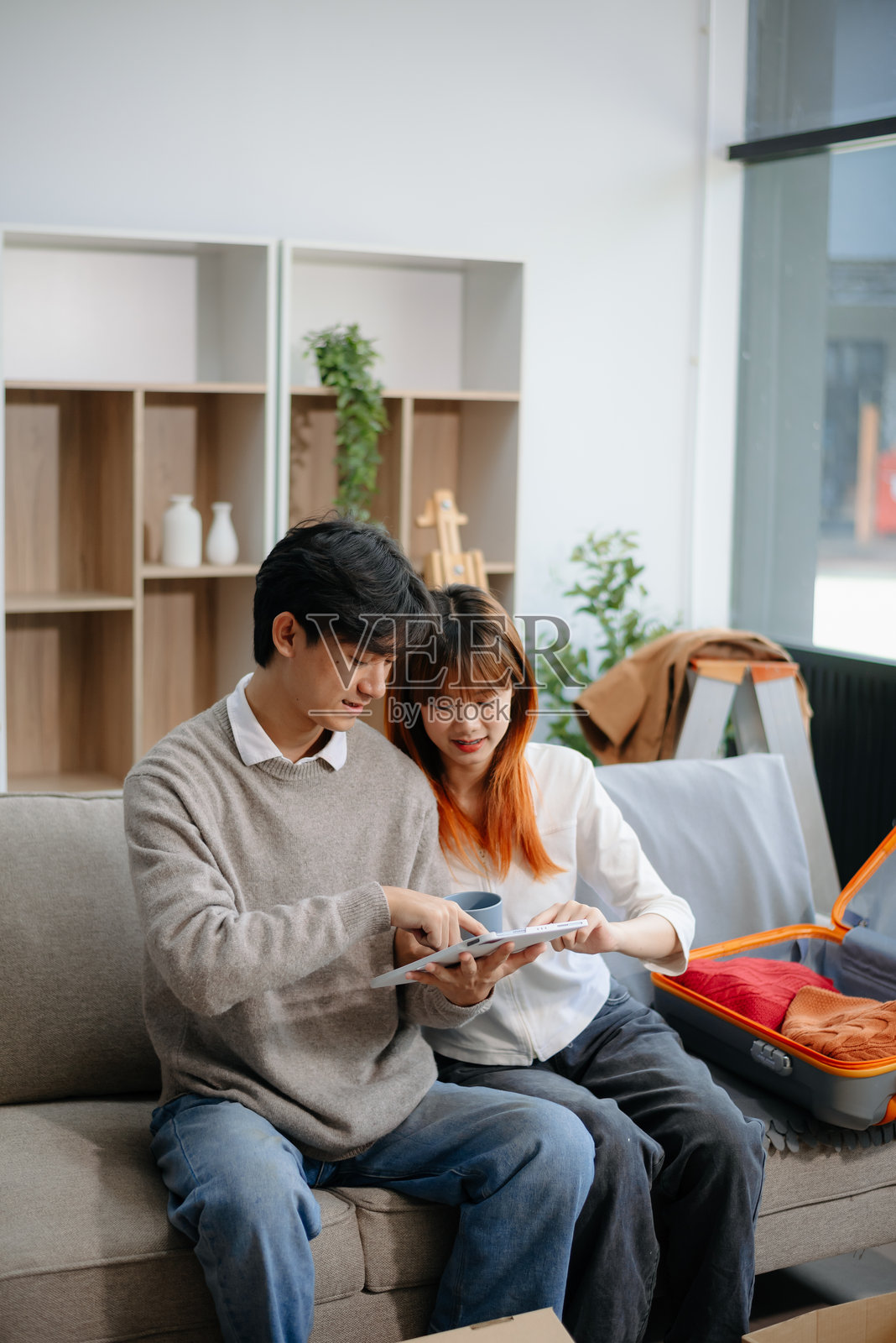 年轻情侣在温馨的客厅里准备搬家，打包箱子和行李箱。非常适合搬迁主题。照片摄影图片