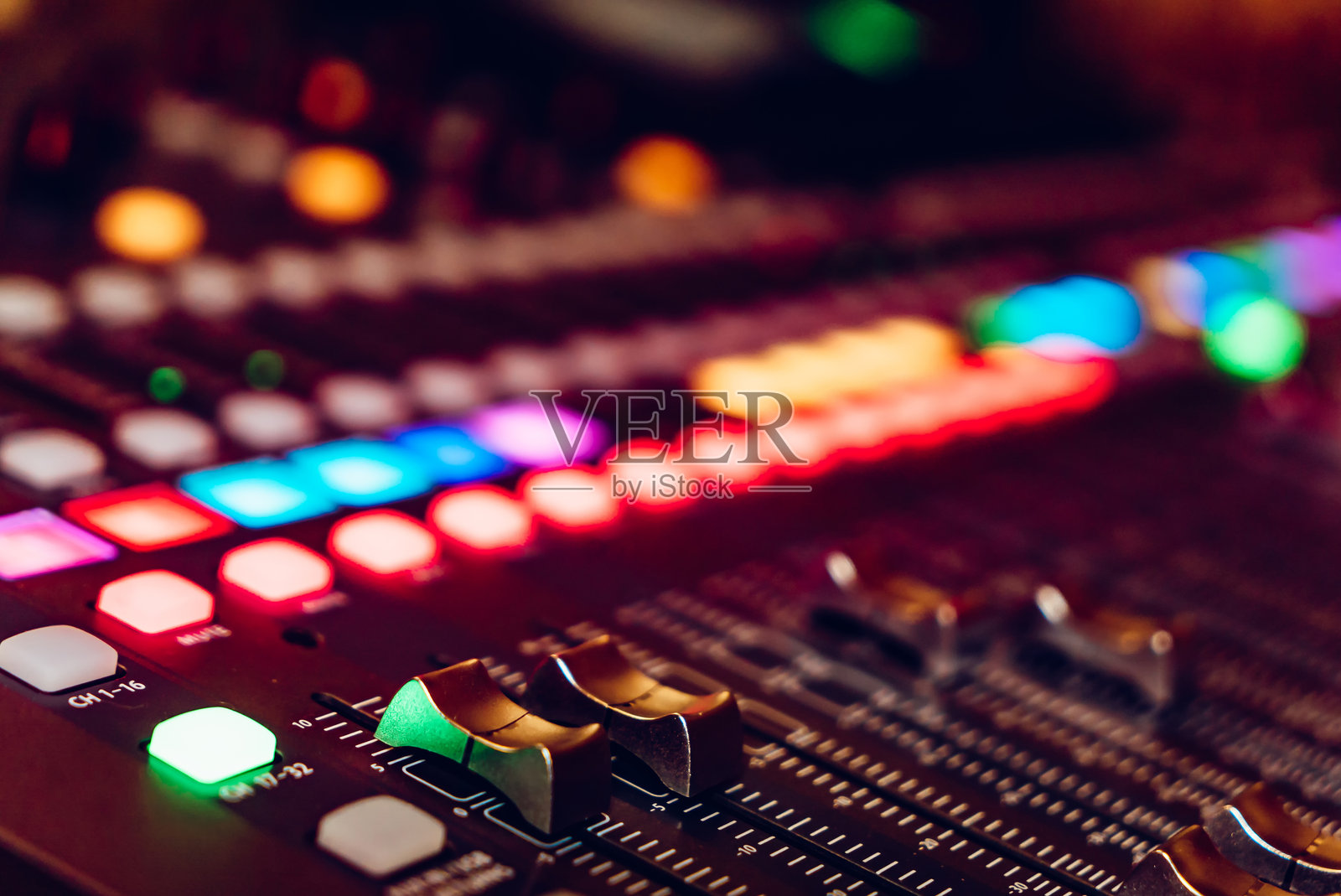 音频混音台的特写，带有五颜六色的按钮和旋钮。音频混音台的详细视图，展示了明亮的发光按钮和旋钮。照片摄影图片