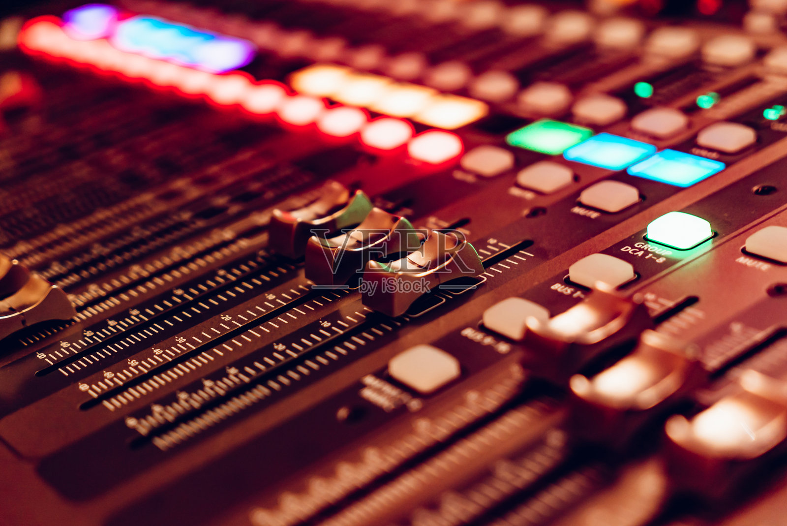 专业音频混音器在录音过程中特写。音频混音台上的彩色按钮和滑块正在使用中。照片摄影图片