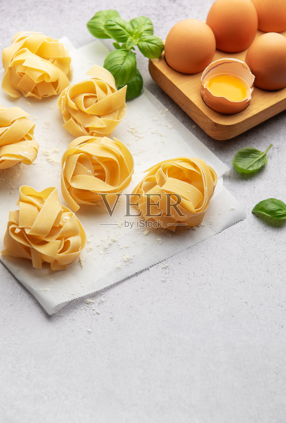 新鲜的宽面条饺子与鸡蛋和罗勒叶放在烘焙纸上照片摄影图片