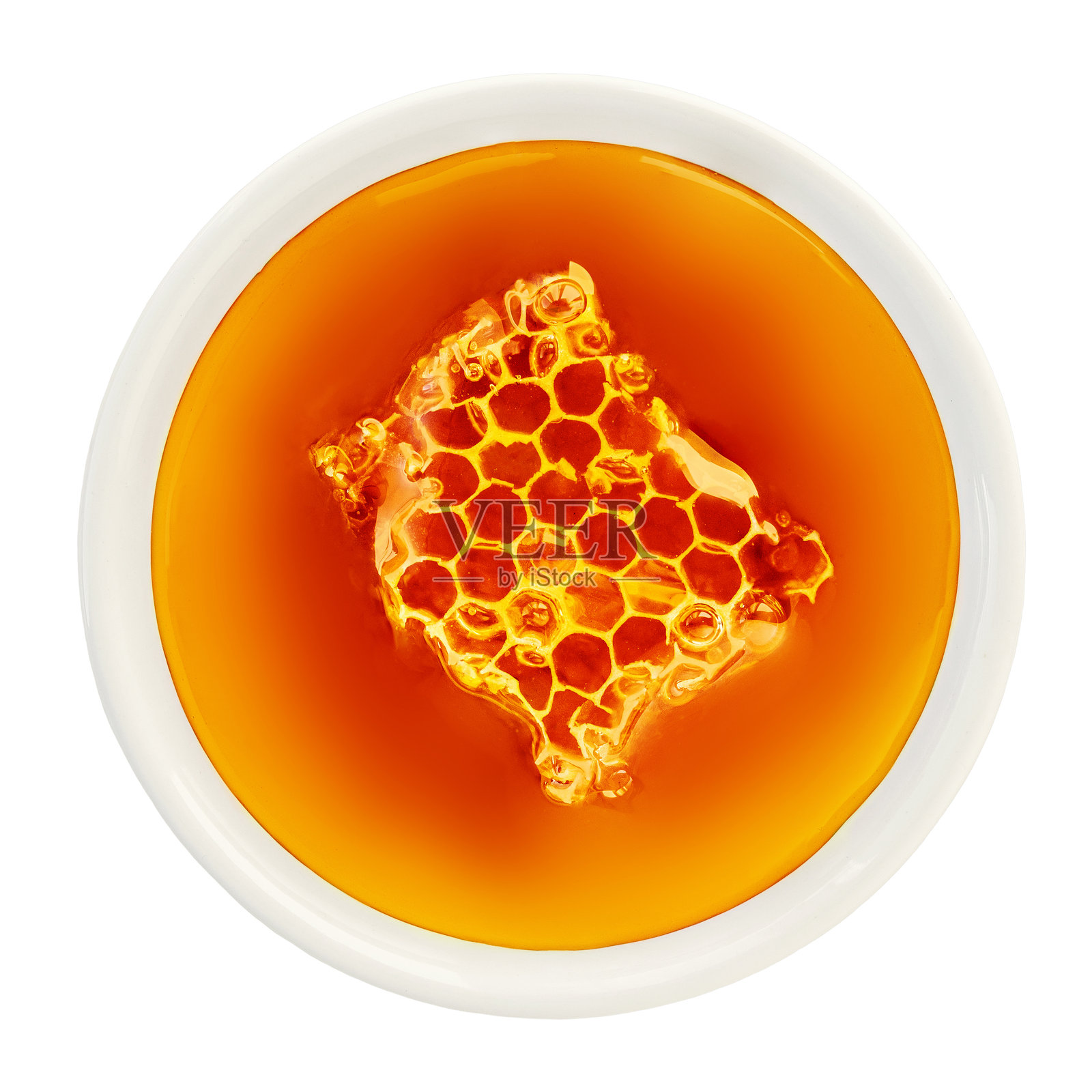 一碗甜蜜的蜂蜜，里面浸泡着蜂巢，背景为白色。蜂蜜巢在蜂蜜糖浆中流动的俯视图。照片摄影图片