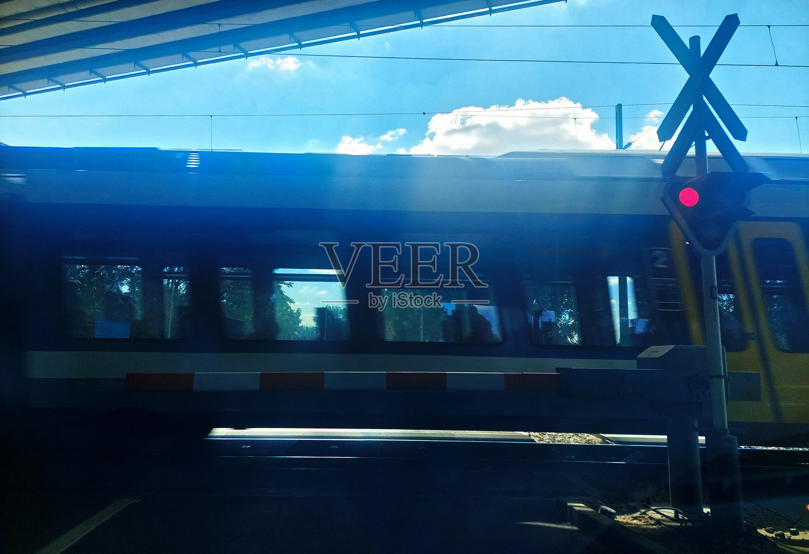 一个铁路道口，有停车标志和道闸，火车以高速通过。照片摄影图片