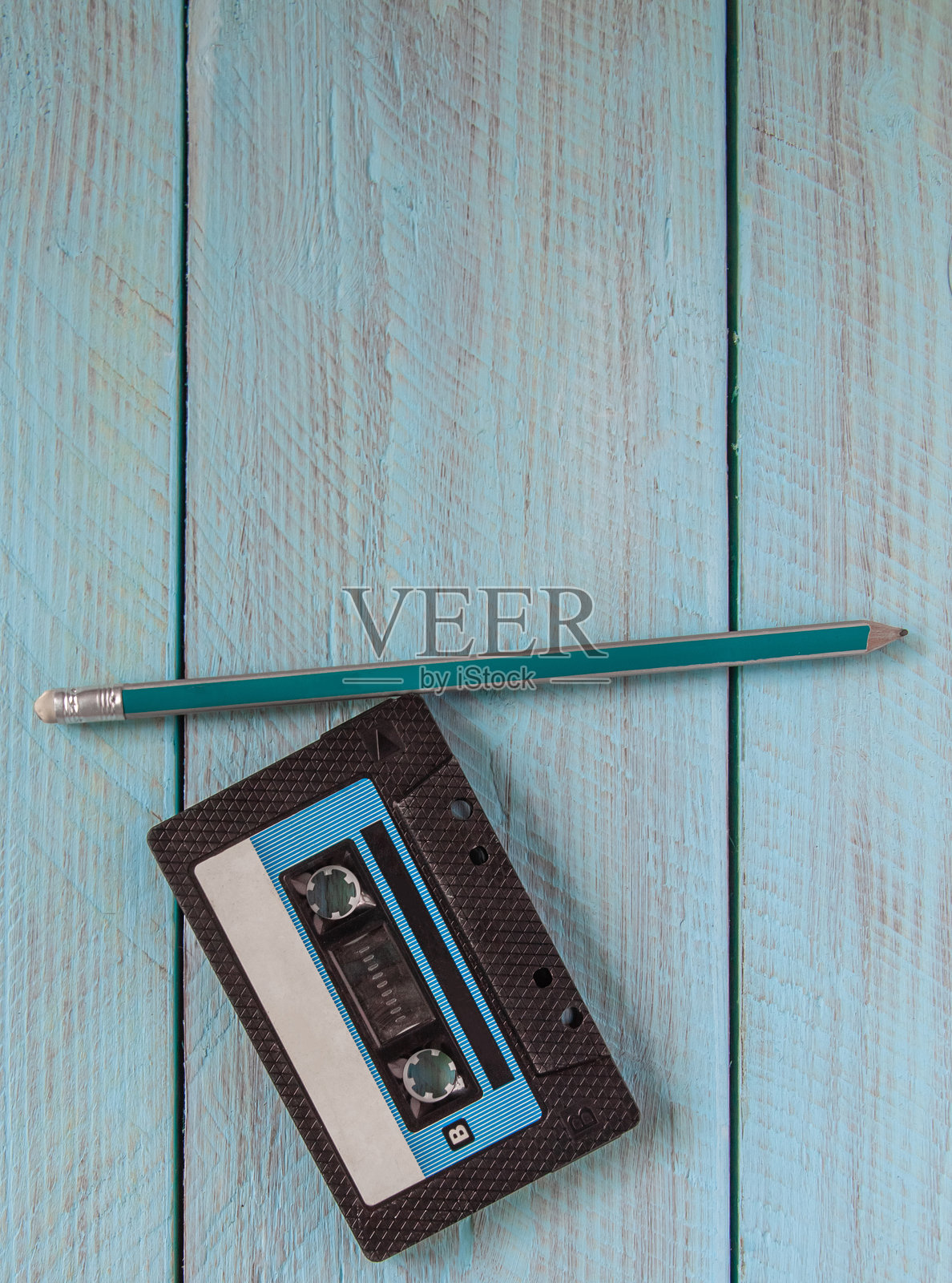 一卷黑色录音带和一支简单的铅笔放在蓝色木质背景上照片摄影图片