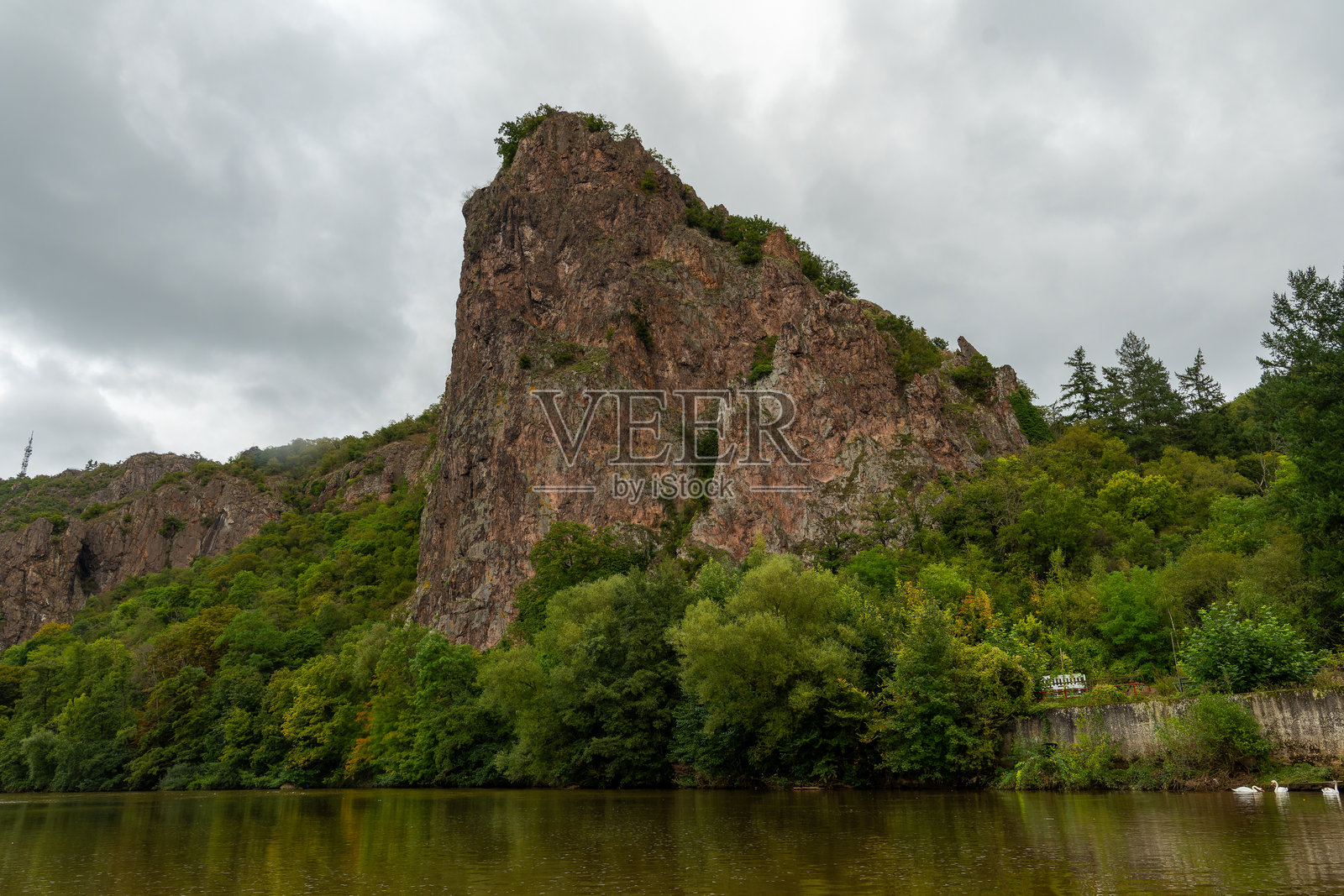 有岩石表面的山，几棵树。天空多云，山上覆盖着绿色植被。照片摄影图片