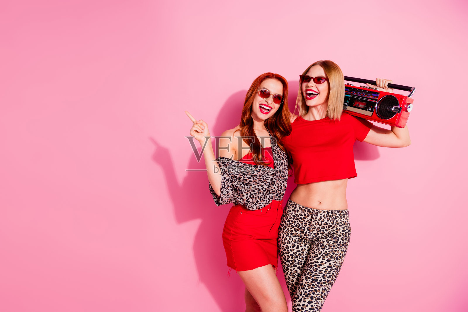 穿着时尚衣服的美丽快乐女孩们在粉色背景上庆祝派对照片摄影图片