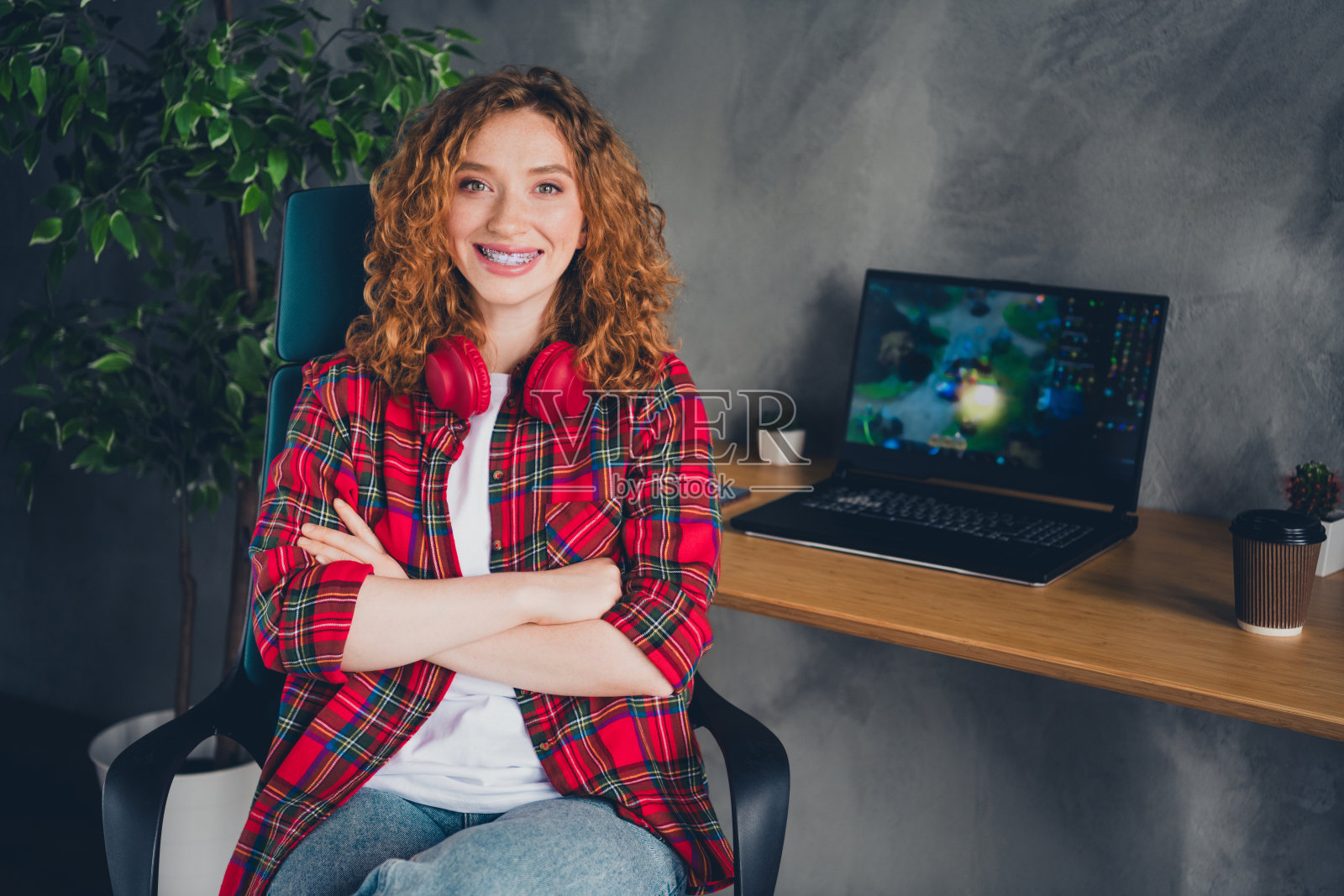 年轻女性在家办公环境中戴着红色耳机微笑照片摄影图片