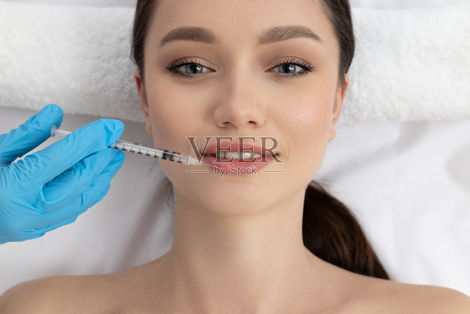 医生给年轻女孩注射肉毒杆菌。照片摄影图片