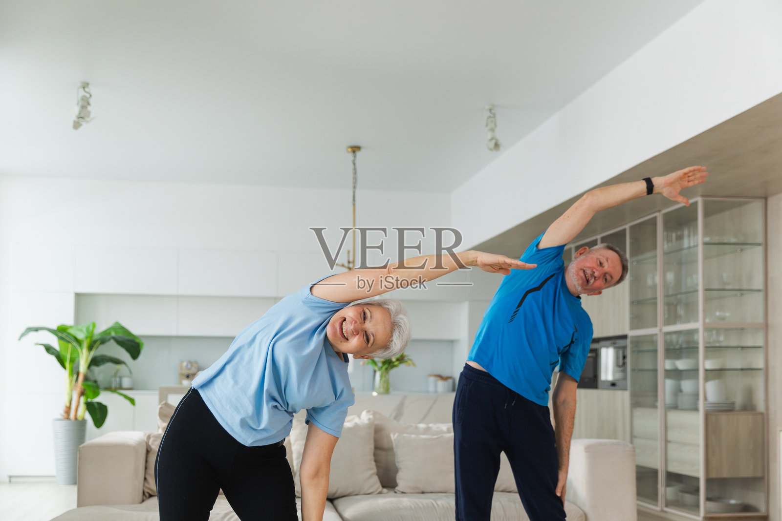 健身训练。成熟健康的老年夫妇在家进行运动锻炼。中年夫妻正在进行训练锻炼。健康护理健康生活方式。老年人康复锻炼。照片摄影图片