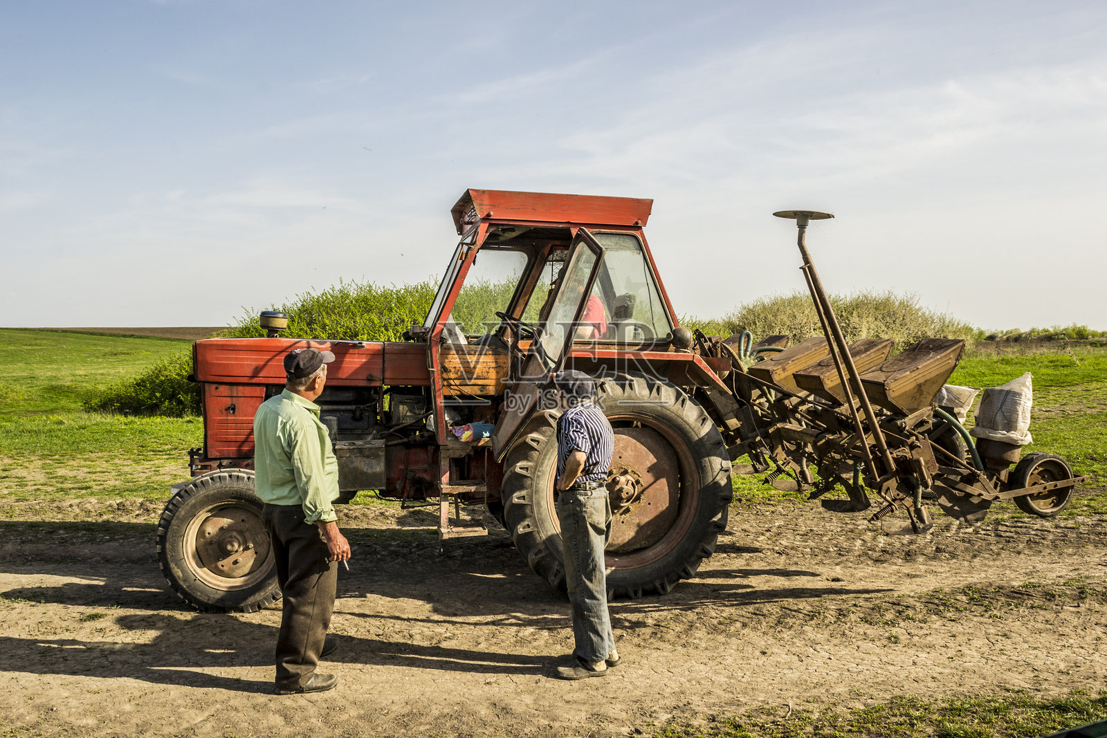 三名男子站在一台旧拖拉机前照片摄影图片