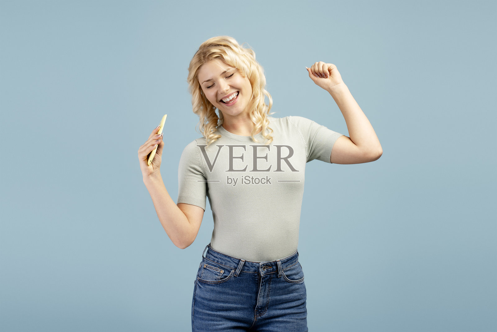 快乐微笑的年轻女孩肖像，青少年手持手机，听音乐，跳舞照片摄影图片