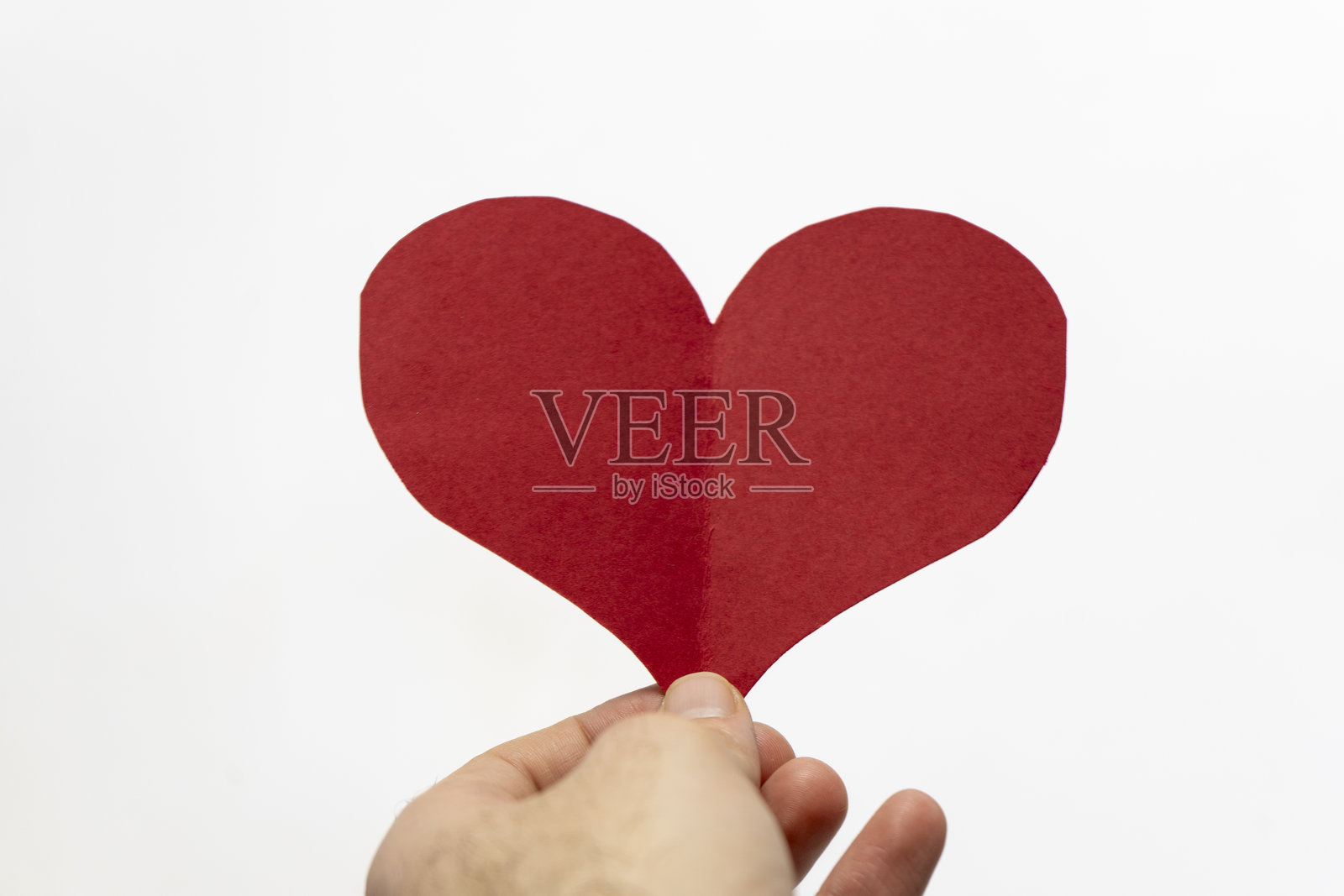 白色背景下手中握着红色纸心。情人节概念照片摄影图片