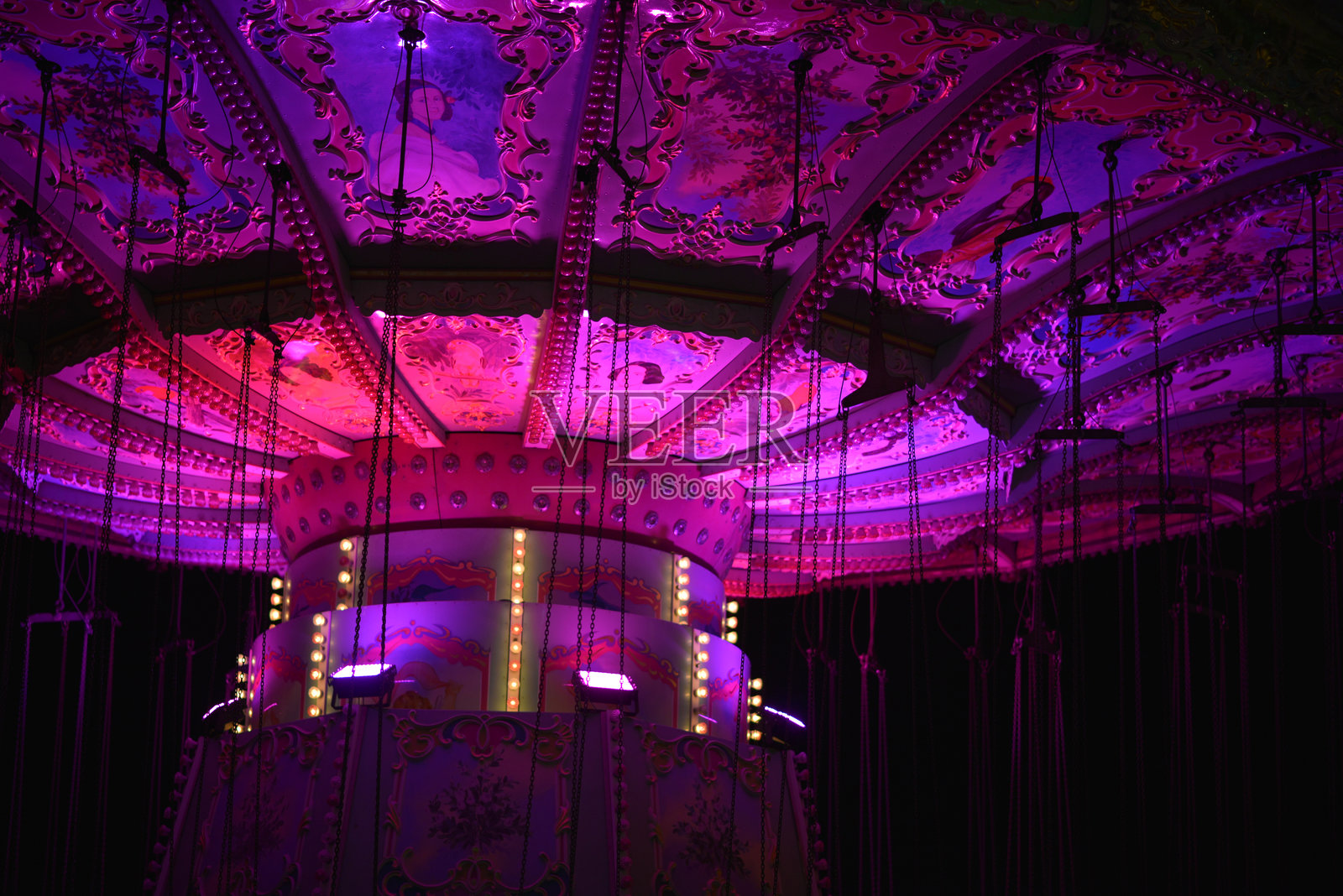 维也纳普拉特游乐园的复古风格旋转木马，粉色灯光在傍晚时分闪耀。照片摄影图片