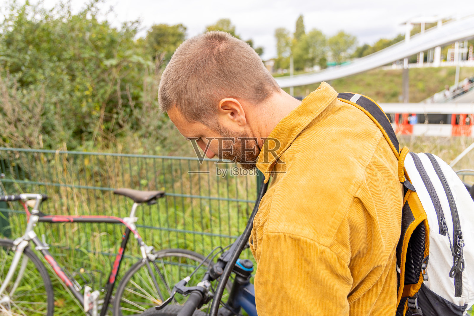 穿着黄色夹克的男子站在现代火车站旁的自行车旁照片摄影图片