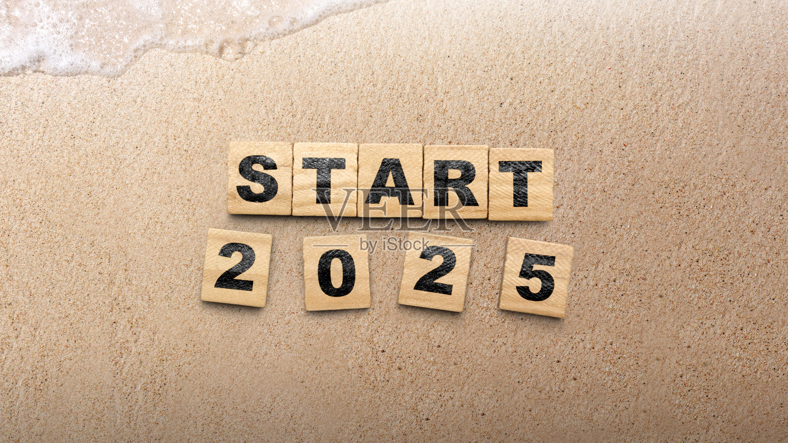 沙滩沙子背景上的木块，上面写着“开始2025”的字样照片摄影图片