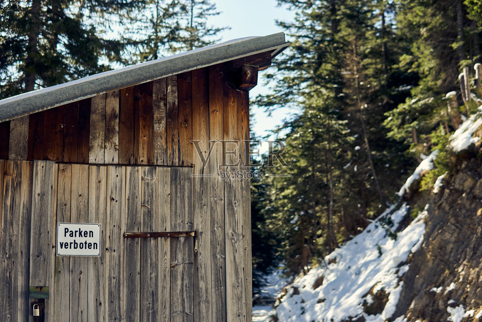 冬季森林中，雪-covered小径旁的木屋，旁边有禁止停车的标志照片摄影图片