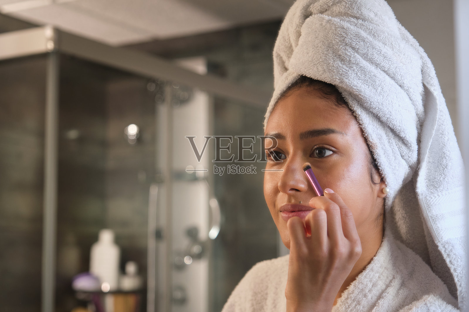 年轻女性在洗澡后在浴室里化妆照片摄影图片