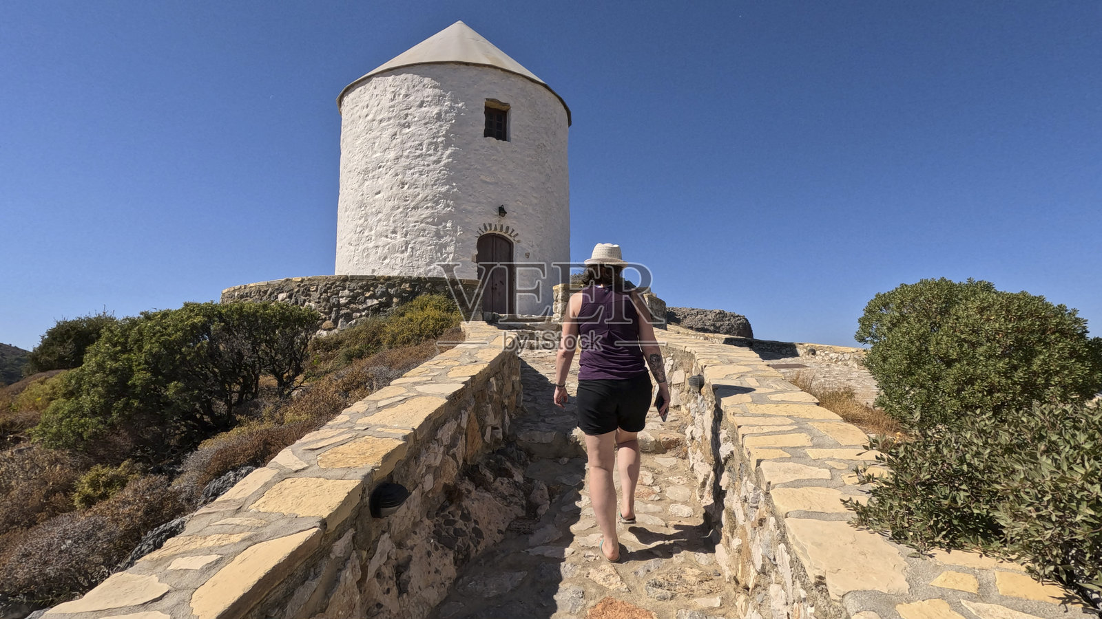 女人在传统希腊建筑附近的小路上散步照片摄影图片