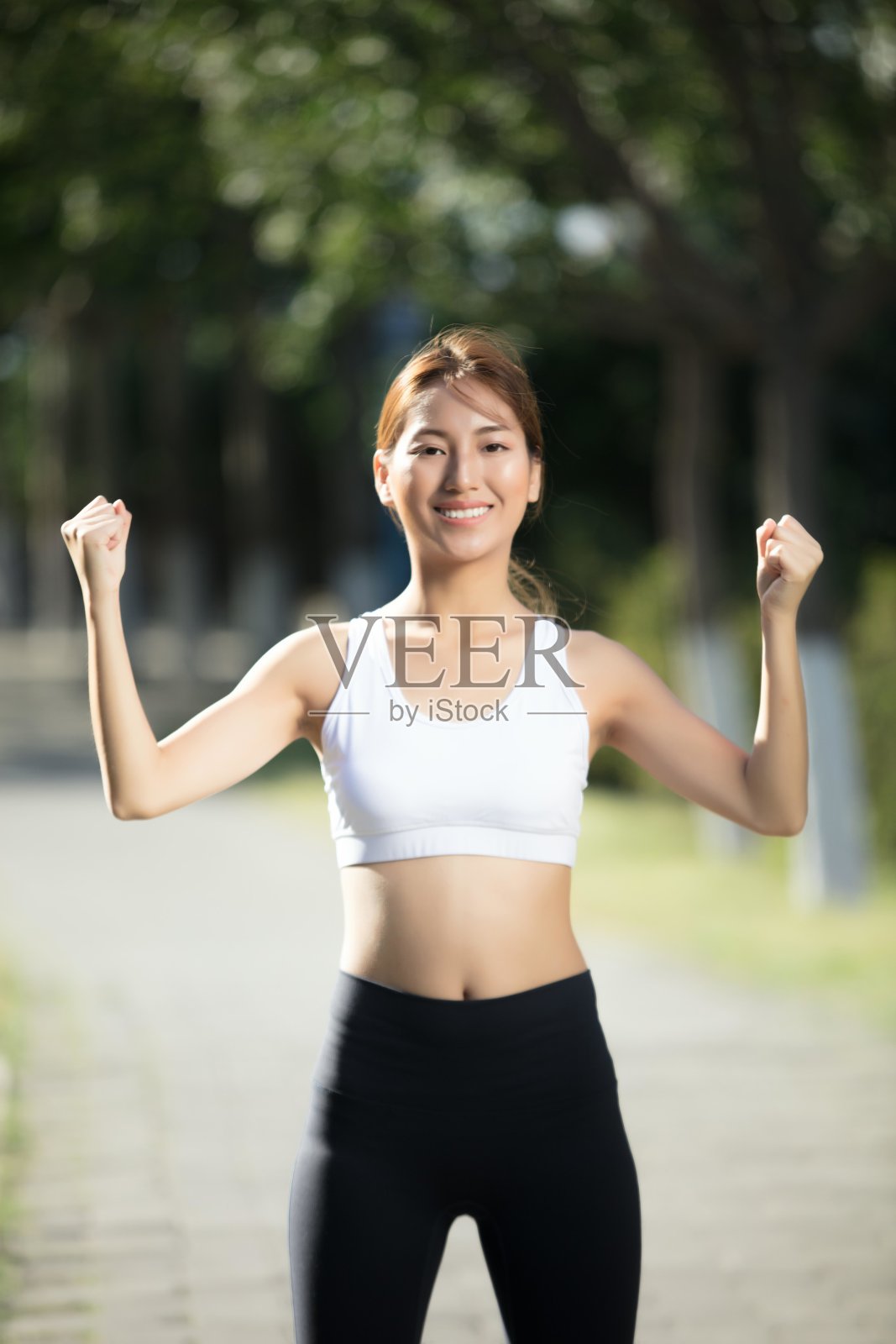 穿着运动服的亚洲女性高举双手庆祝她的成功照片摄影图片