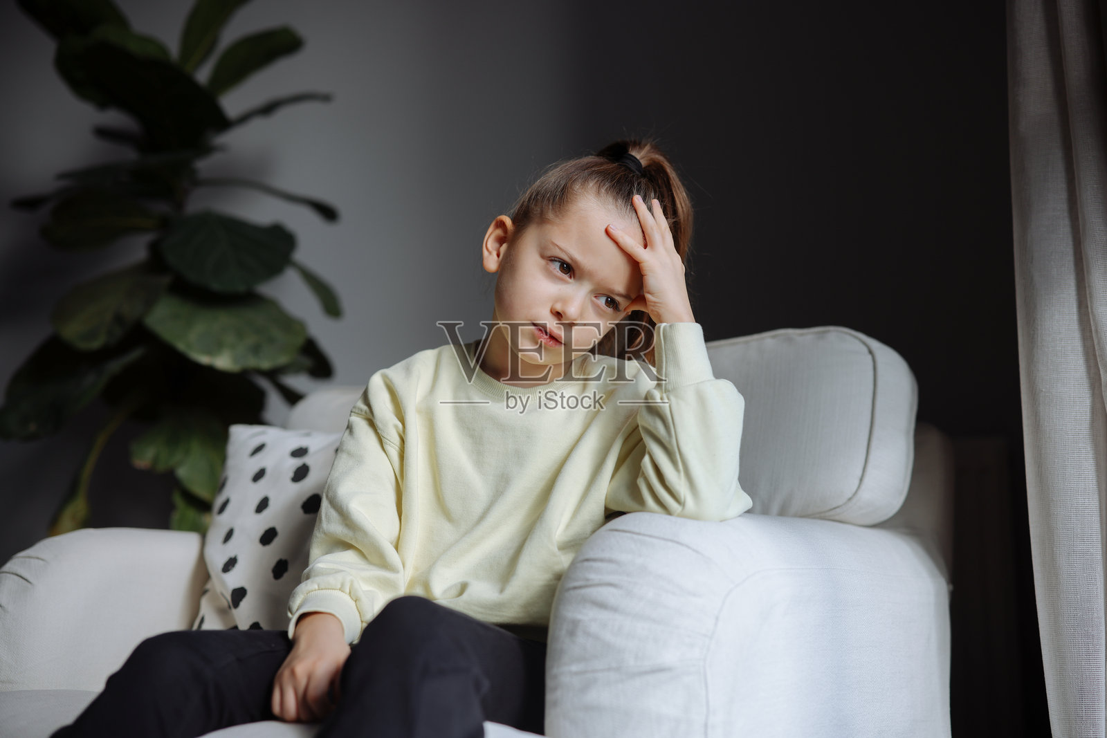 不快乐的小女孩坐在沙发上，思考着问题照片摄影图片