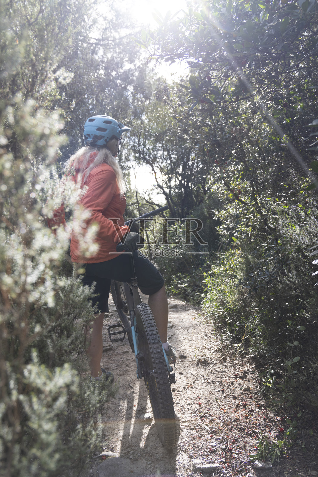 女性在橄榄树林中骑电动山地车暂停。照片摄影图片