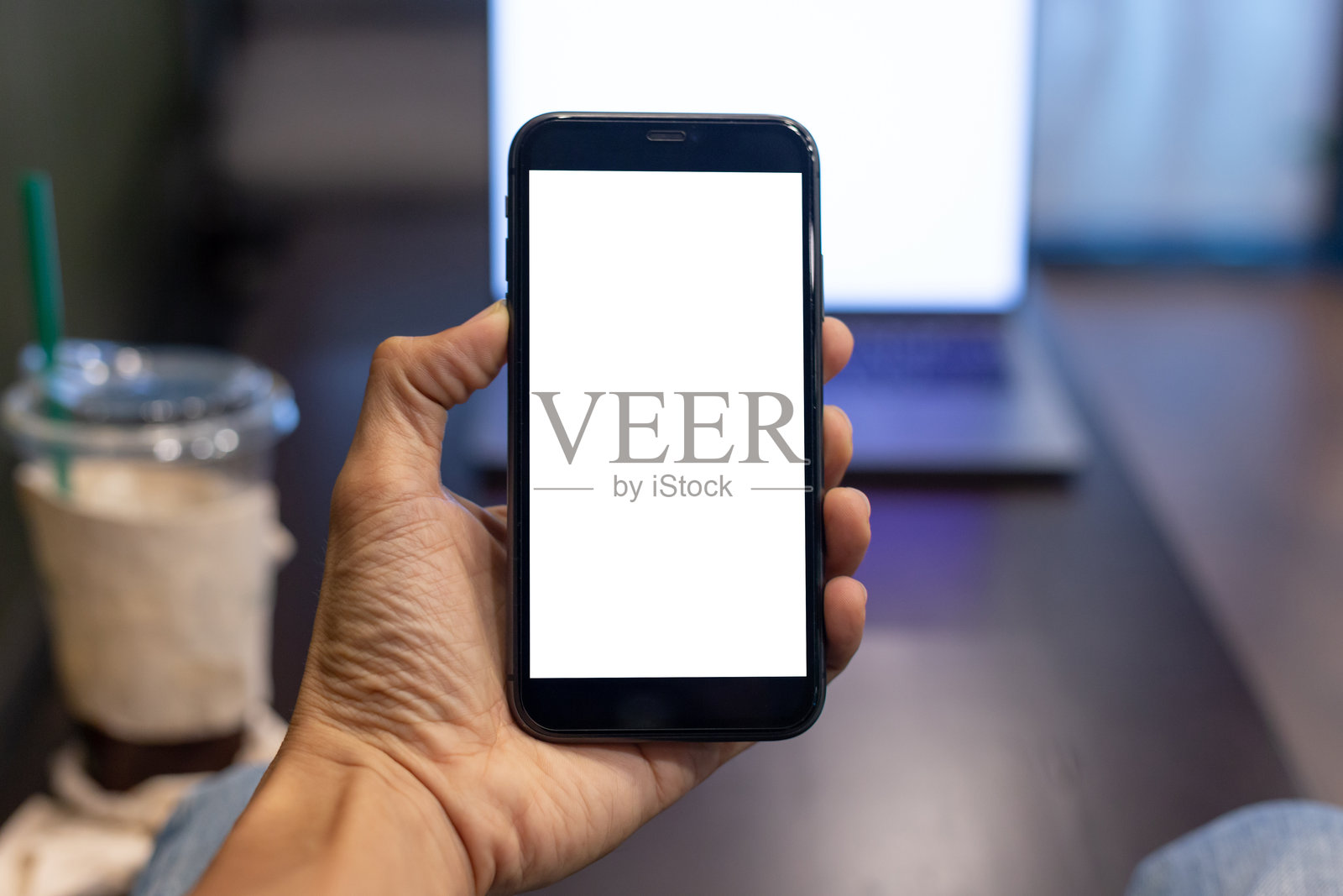 商务人士在咖啡店用手握着一部屏幕空白的智能手机，带有抠图路径。照片摄影图片