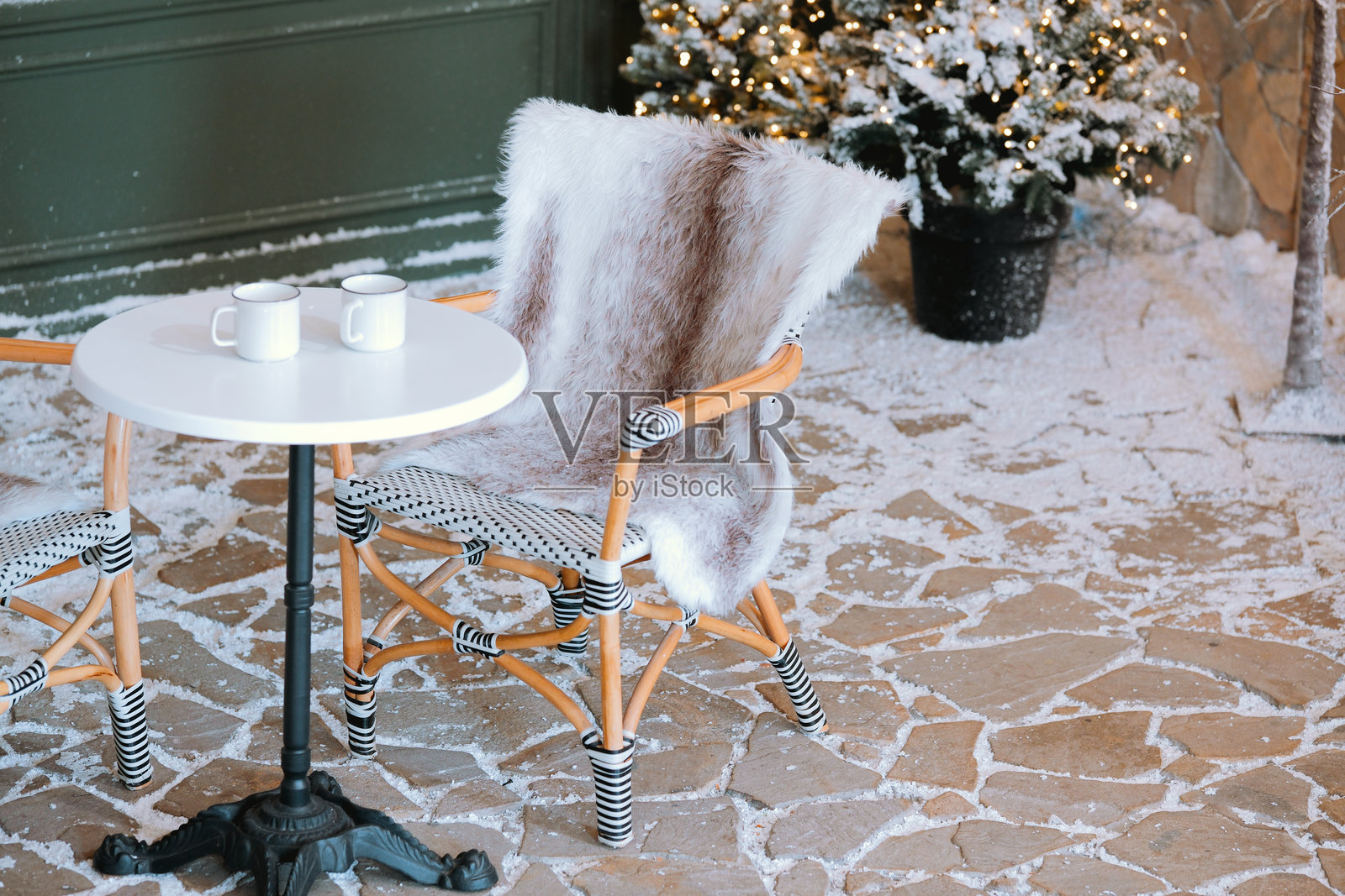温馨的冬季露台，雪景中有一张小桌子和几只杯子照片摄影图片