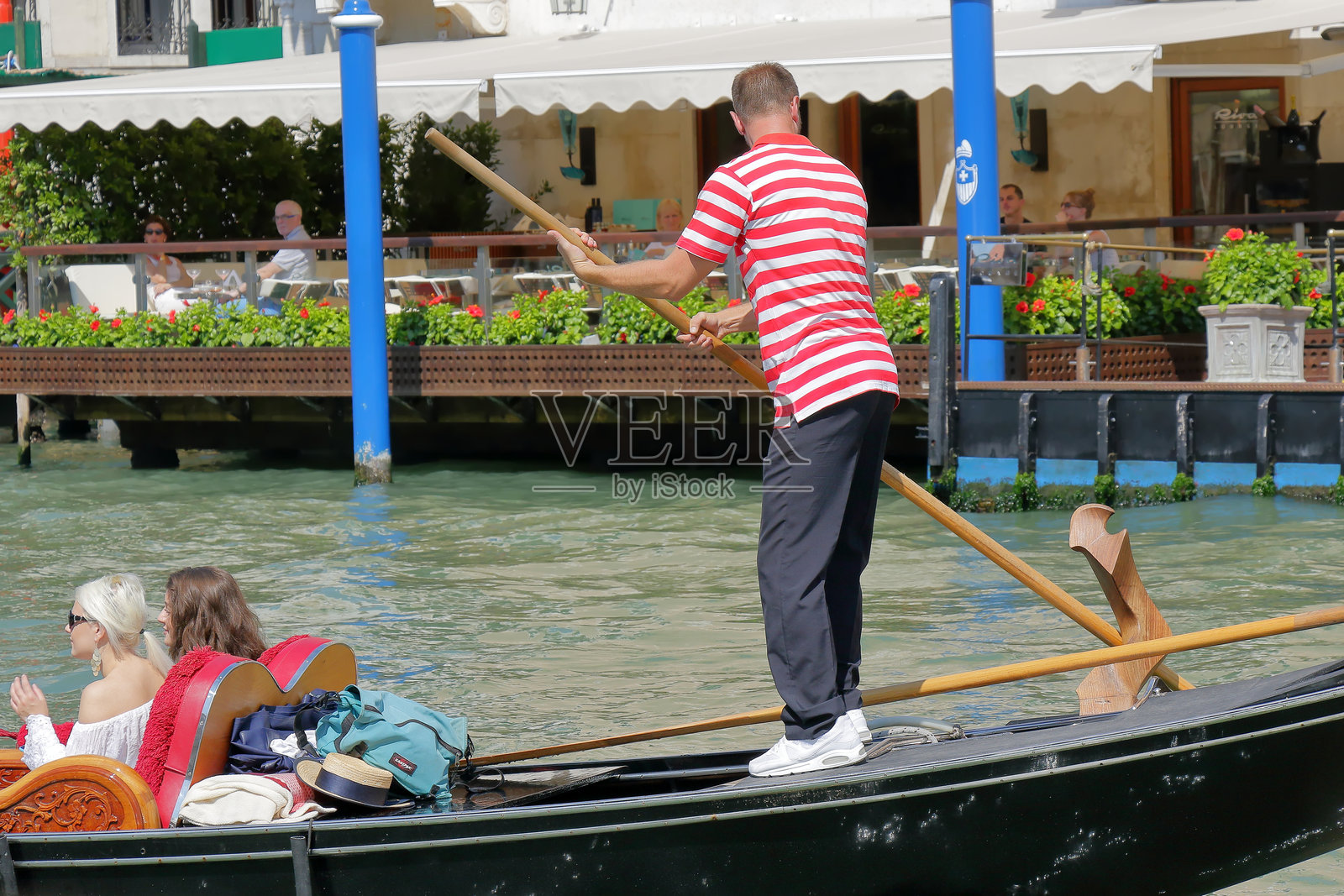 威尼斯,意大利的贡多拉船夫正在划桨,船上有乘客。照片摄影图片