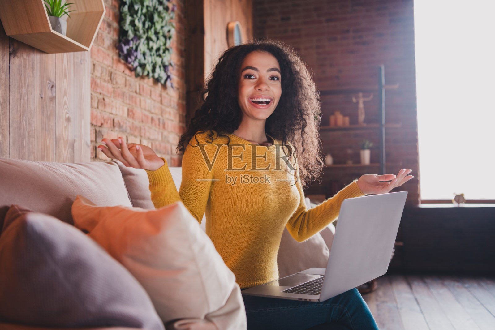 快乐的年轻女性在舒适明亮的公寓里使用笔记本电脑学习，享受阳光和舒适的环境照片摄影图片