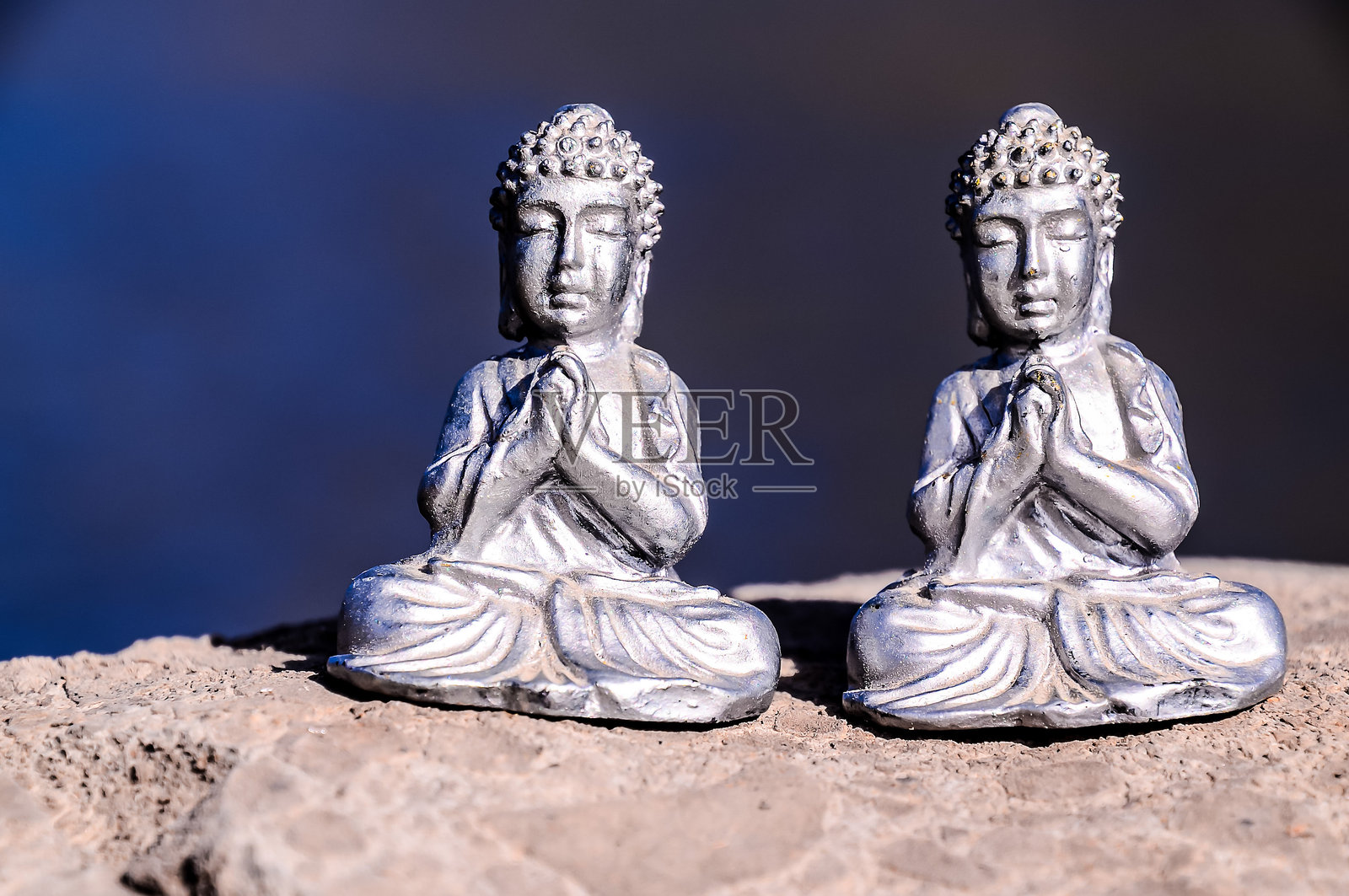 两尊银色佛像坐在岩石上照片摄影图片