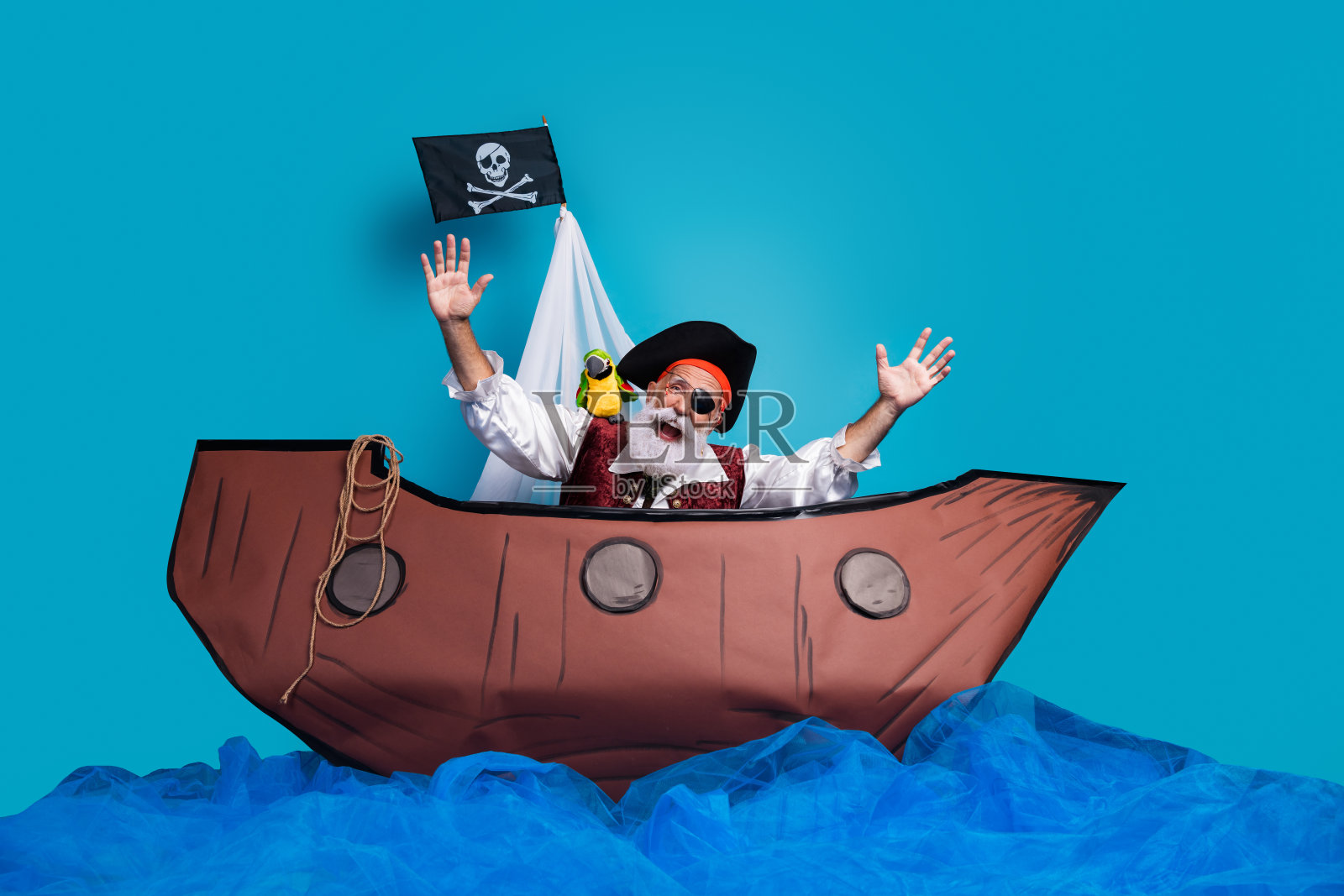 穿着传统中世纪海盗服装的搞笑老年男子，背景为蓝色。照片摄影图片