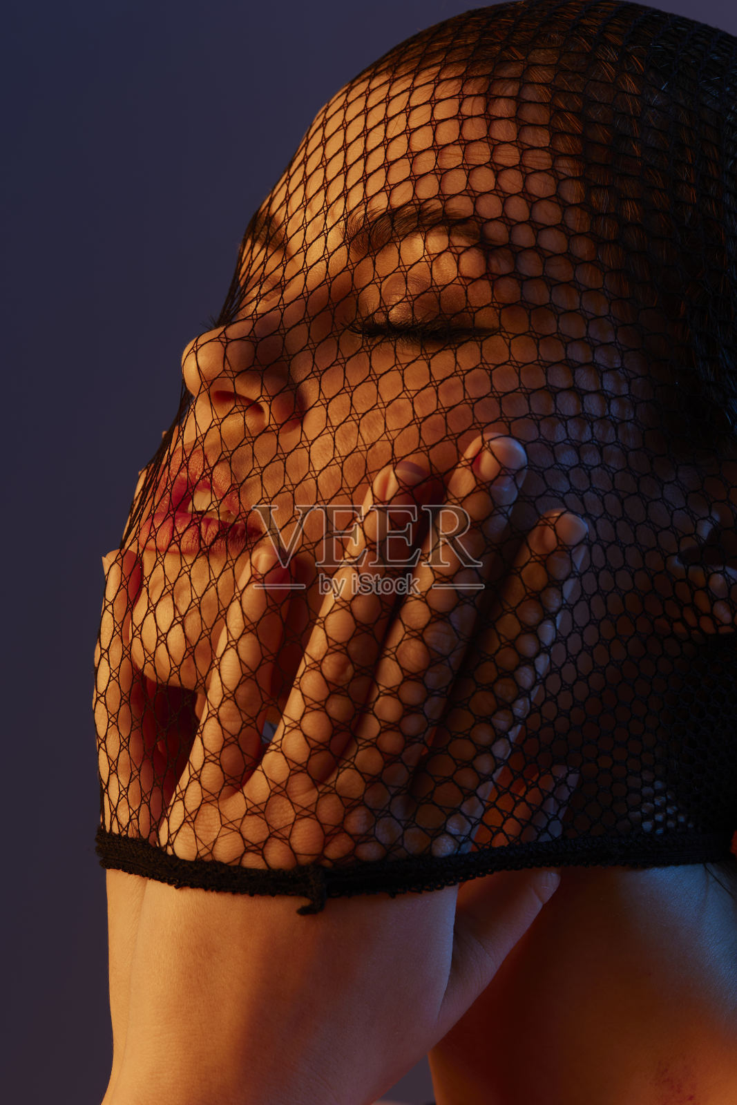 美丽的女子面戴黑色面纱，特写，红色光背景照片摄影图片