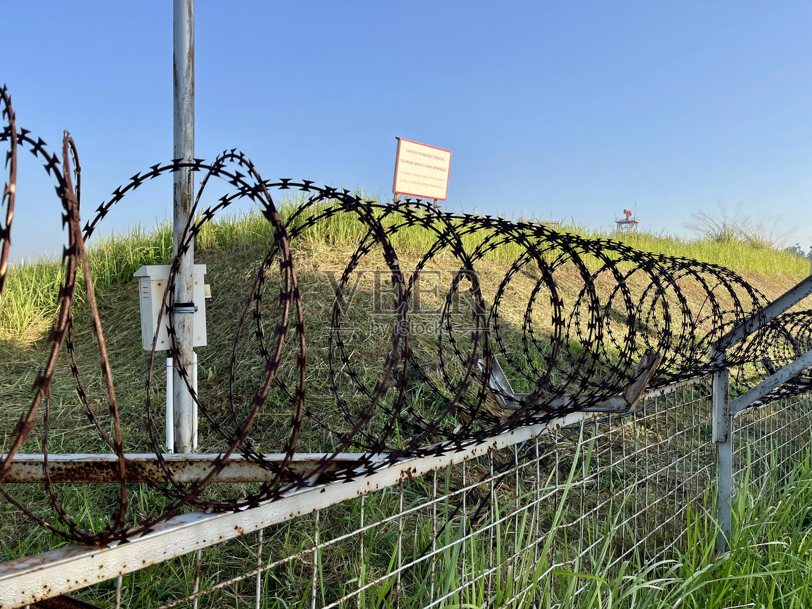 带刺铁丝网的围栏，草地和晴朗的蓝天照片摄影图片