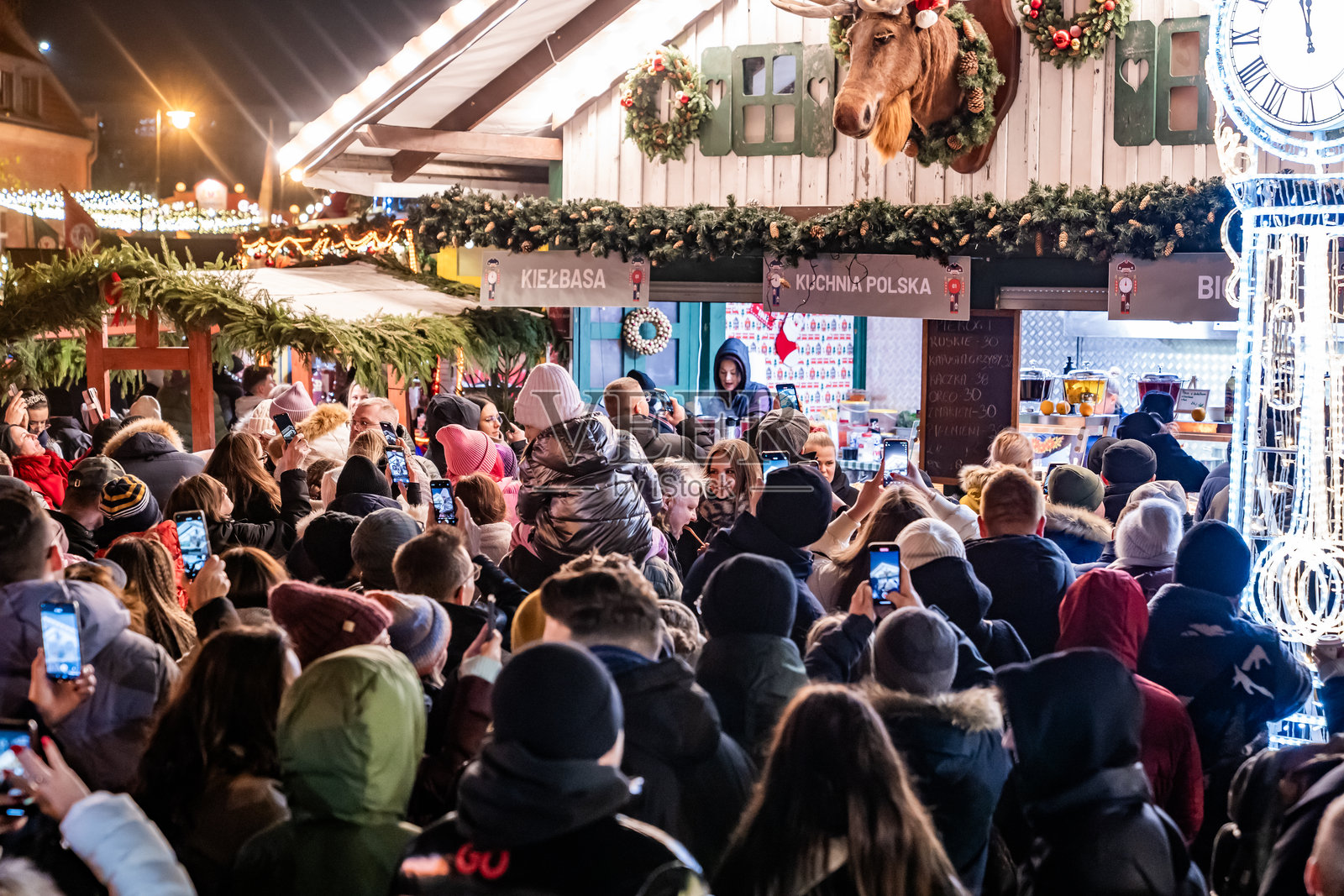 圣诞市场的游客在节日灯光和重叠的人群中探索节日摊位。照片摄影图片