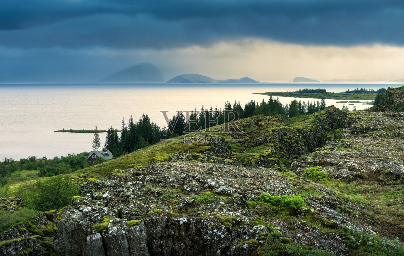 辛格维利尔国家公园的景色，郁郁葱葱的绿地和远处的山脉在戏剧性的天空下。照片摄影图片