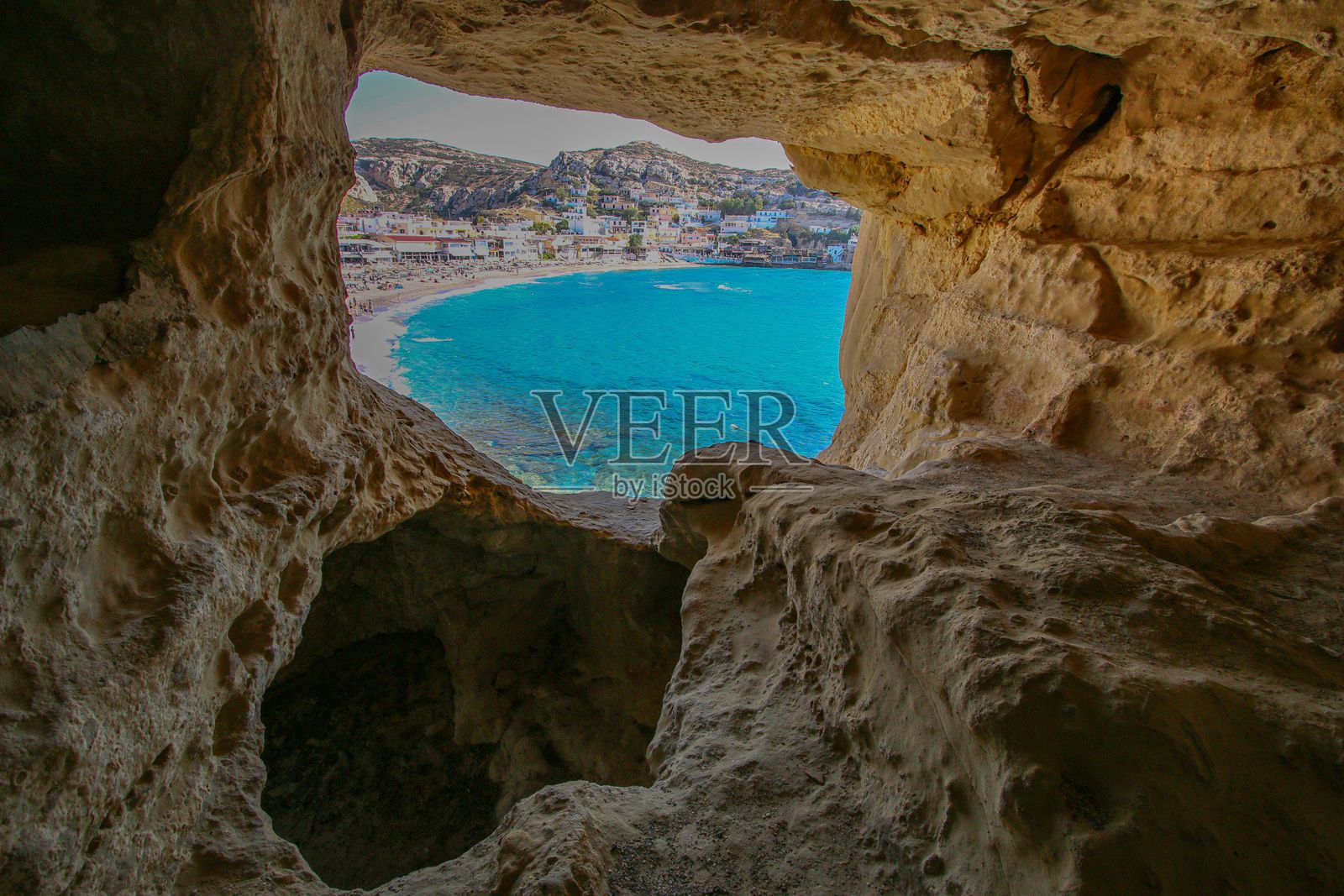 通过岩石洞穴看到的风景海滨小镇景色。照片摄影图片
