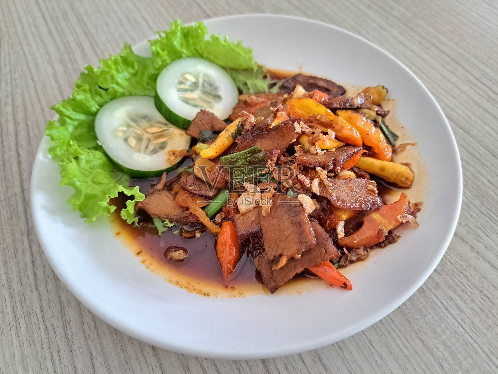 辛辣火爆牛肉炒菜，配料有牛肉、生菜、黄瓜、韭菜、青葱、红辣椒、红椒、洋葱、大蒜、红糖、香菜、胡椒、姜黄、姜、甜酱油和盐。印尼美食菜单。照片摄影图片