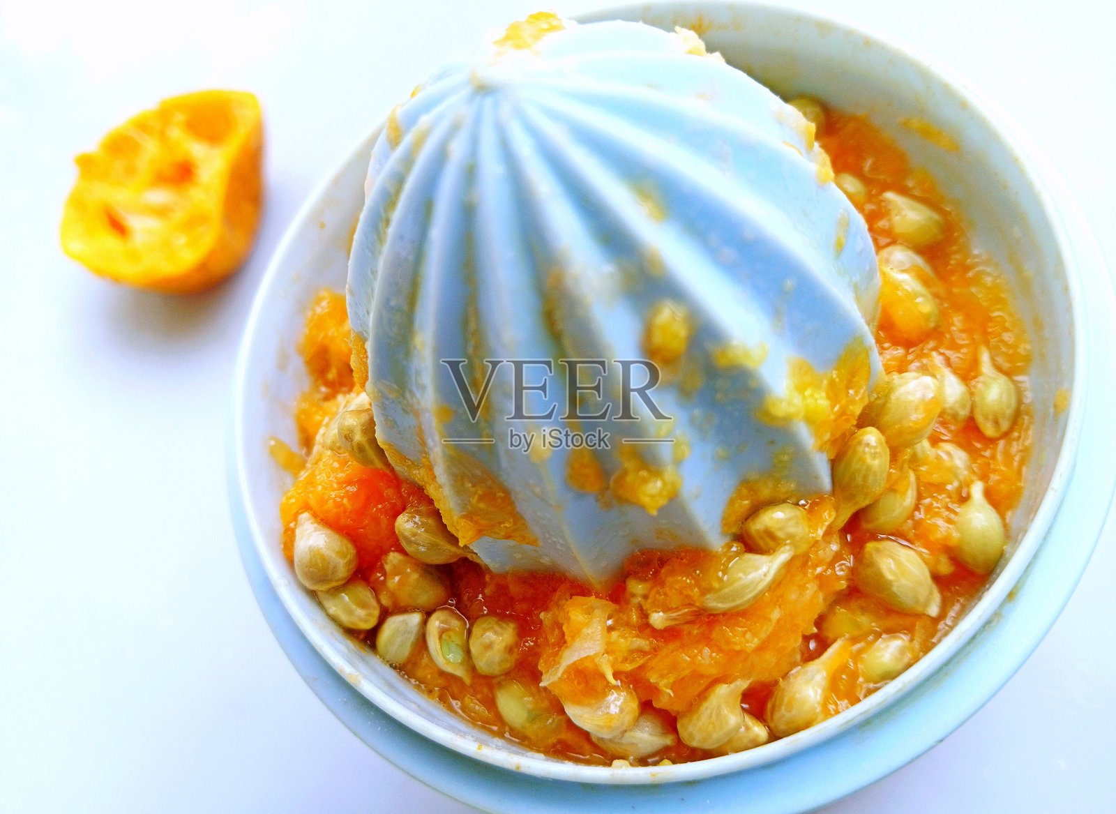 橙子果实种子在榨汁机中 - 饮料准备。照片摄影图片