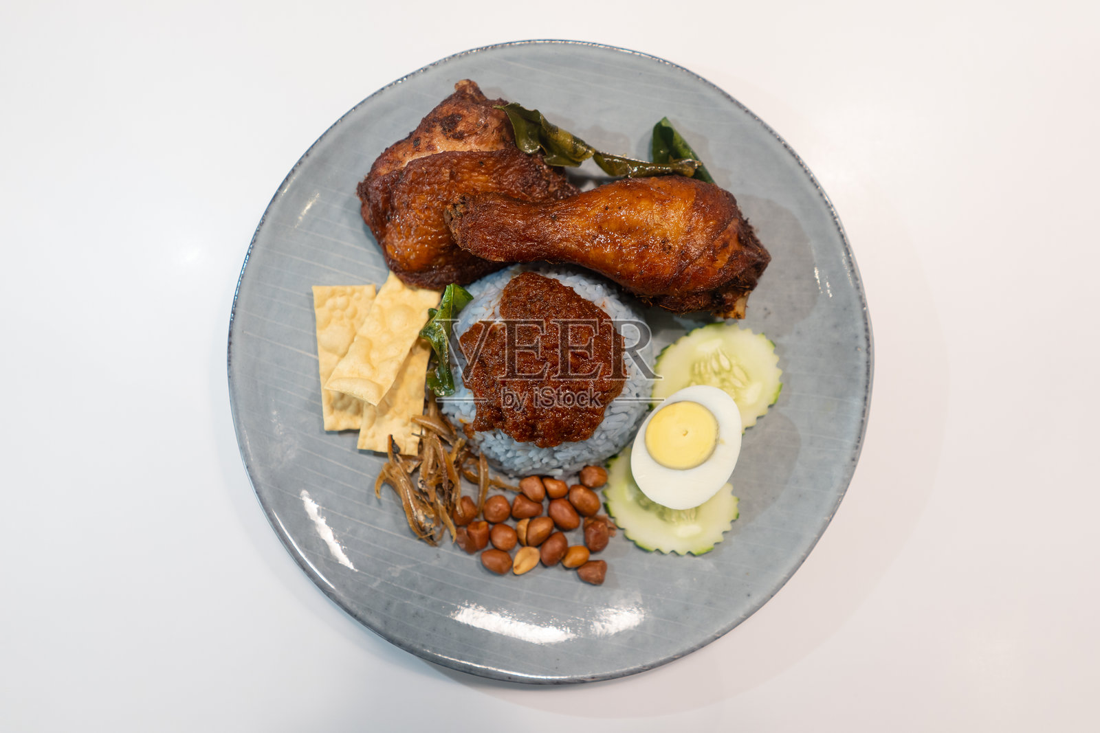 槟城当地美食“椰浆饭”，特色蓝色米饭配上辣椒酱，搭配炸鸡腿、鱼饼、煮鸡蛋、黄瓜和花生。照片摄影图片