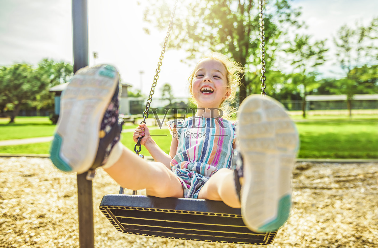 快乐的三岁女孩在秋千上。快乐的孩子在游乐场。照片摄影图片