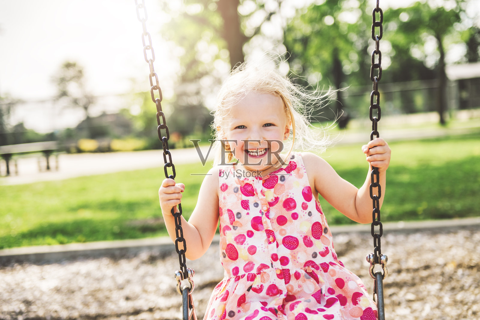 快乐的三岁女孩在秋千上。快乐的孩子在游乐场。照片摄影图片