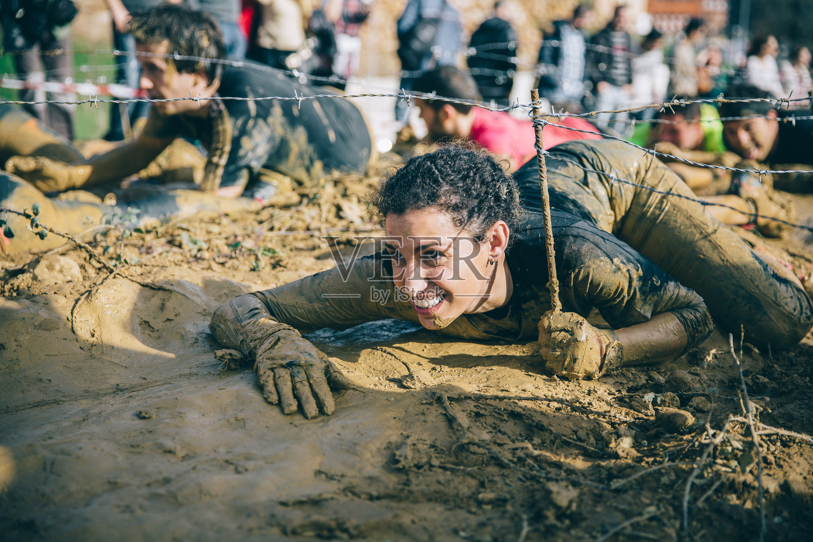 在极限测试中，跑者爬过铁丝网照片摄影图片