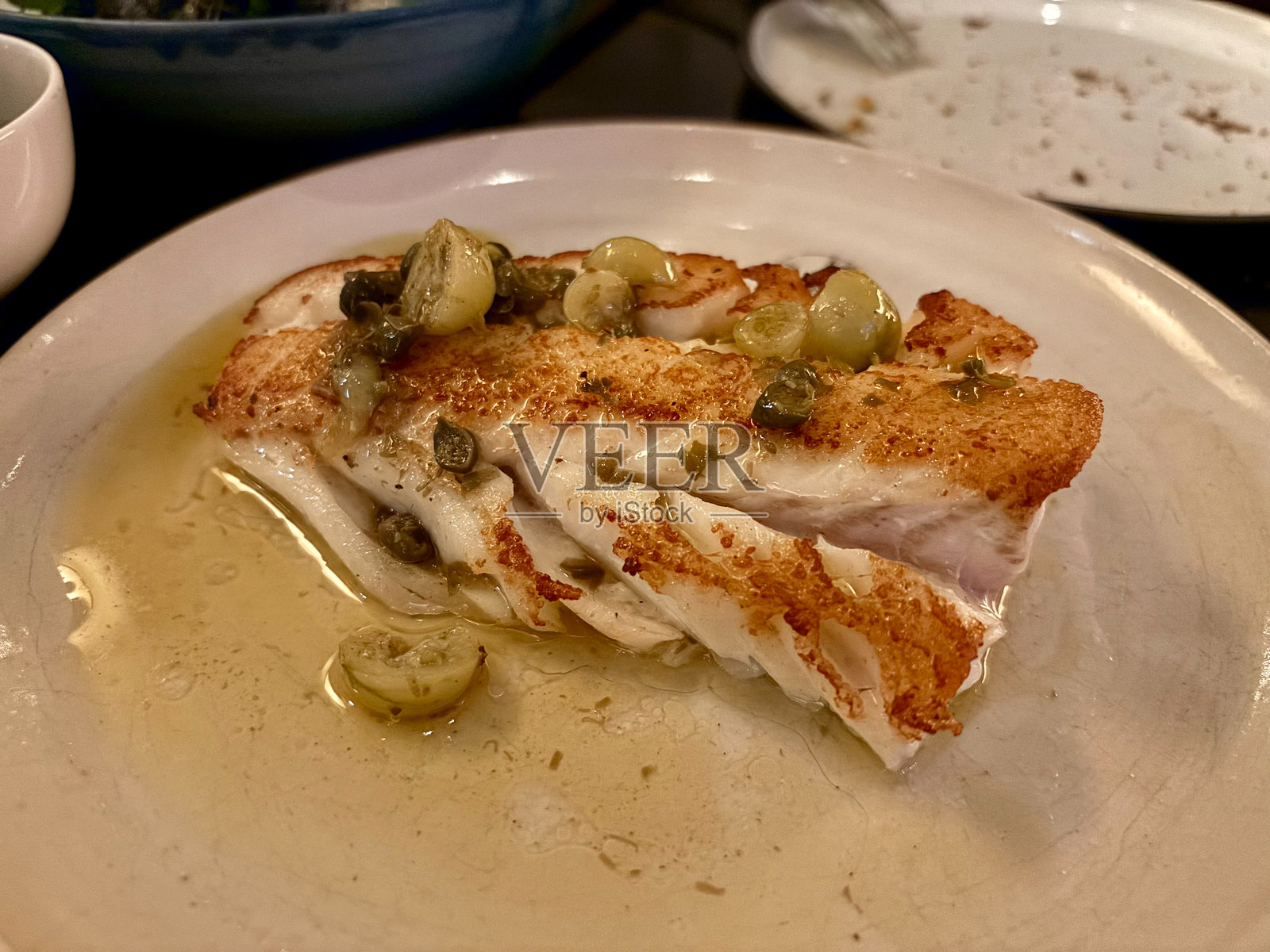 炸鱼片，大西洋鳕鱼配刺山柑和青番茄。照片摄影图片