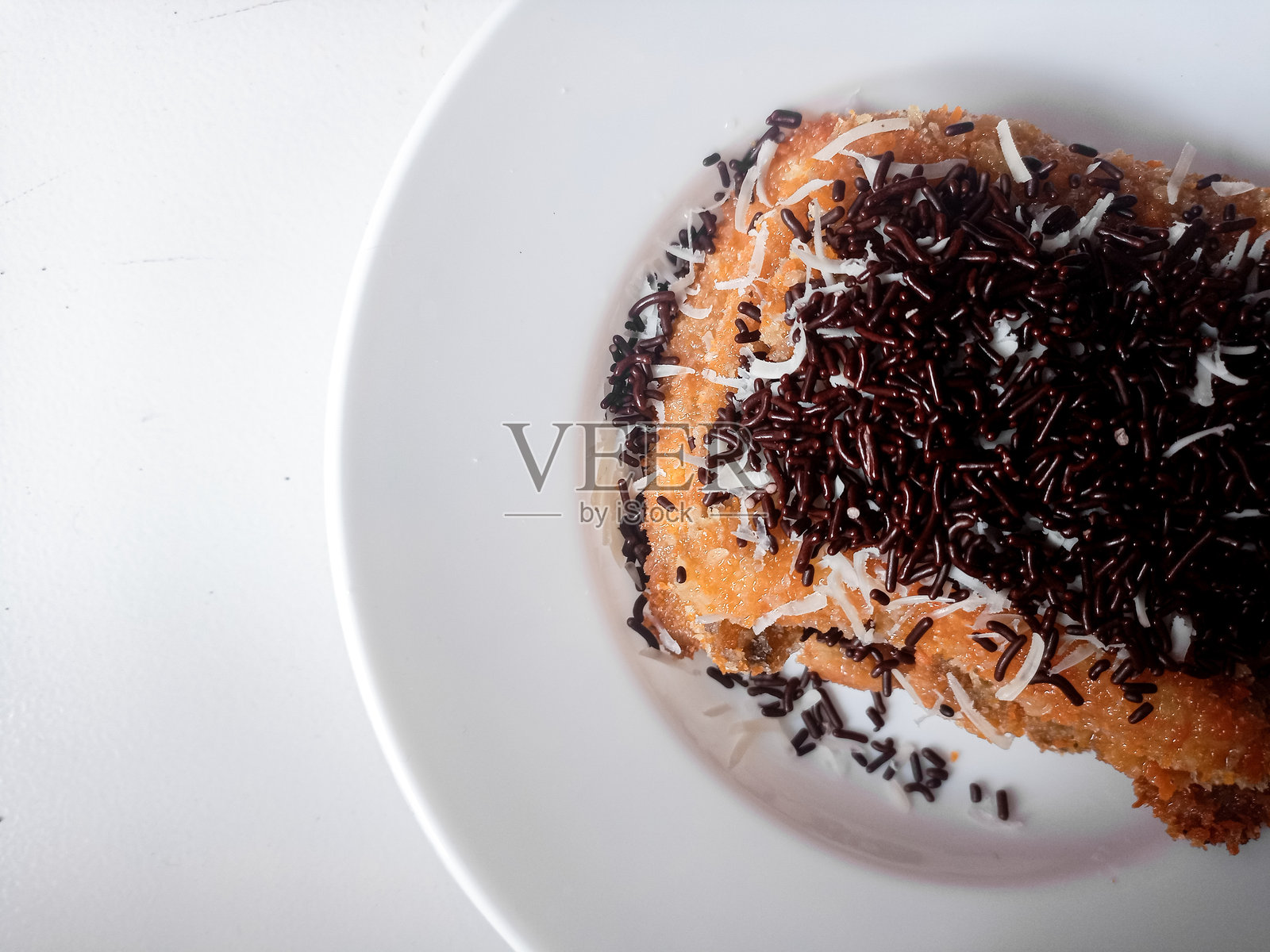 烤香蕉巧克力奶酪，配有巧克力撒粉和切达奶酪碎，摆放在白色盘子上。照片摄影图片