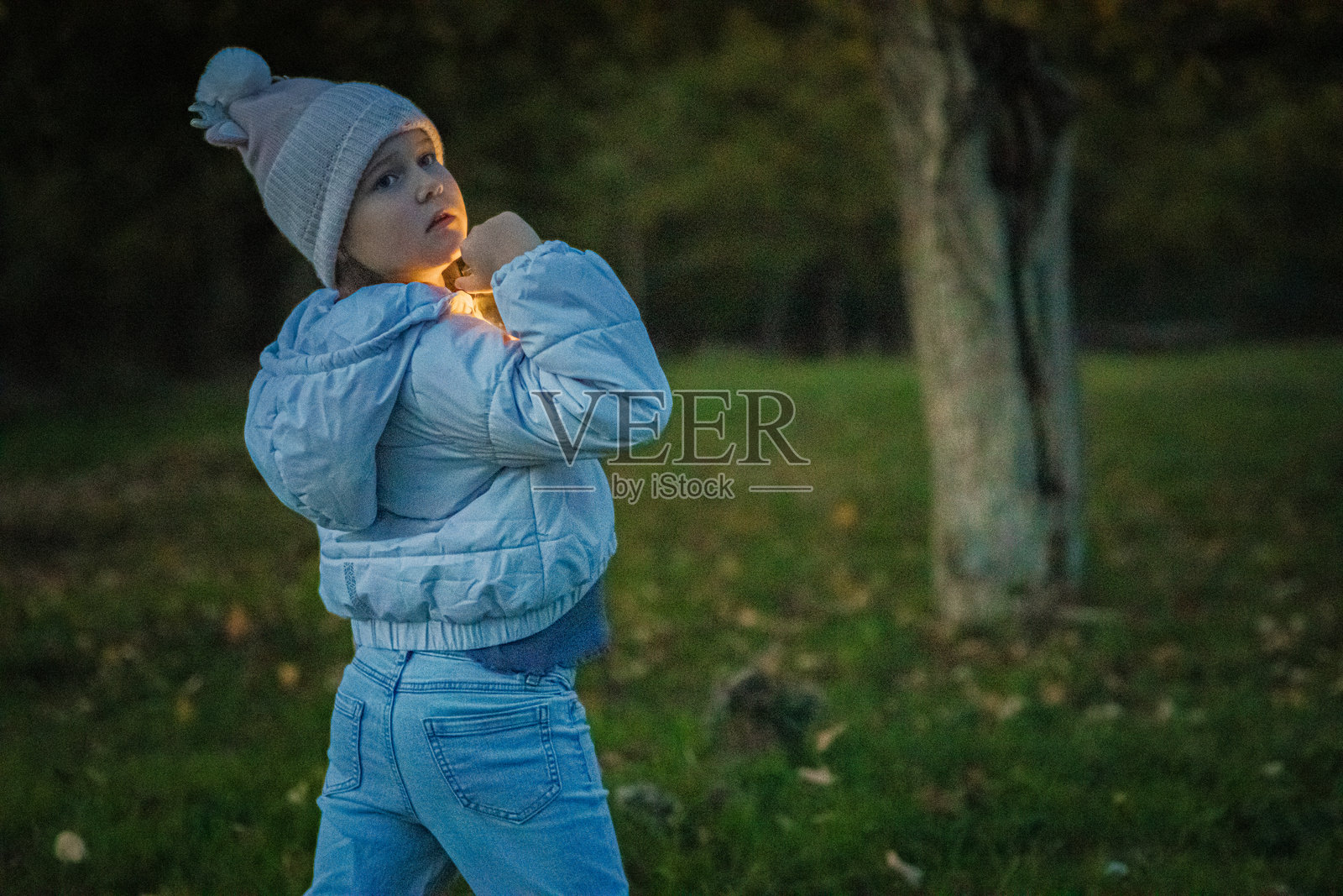 神奇的时刻。可爱的小女孩在后院里玩耍，手中拿着装有灯光的罐子。圣诞节的灯光照亮了她快乐的脸庞。照片摄影图片