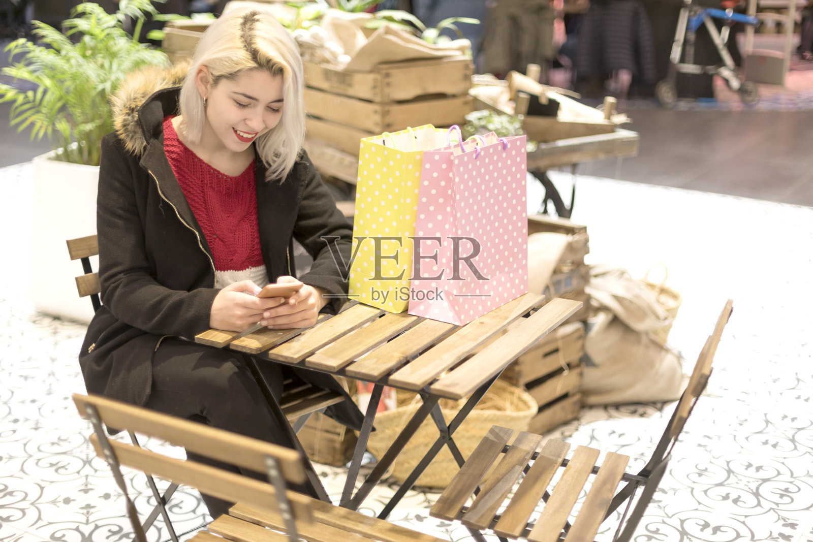 女性在室内咖啡桌旁购物并使用智能手机。照片摄影图片