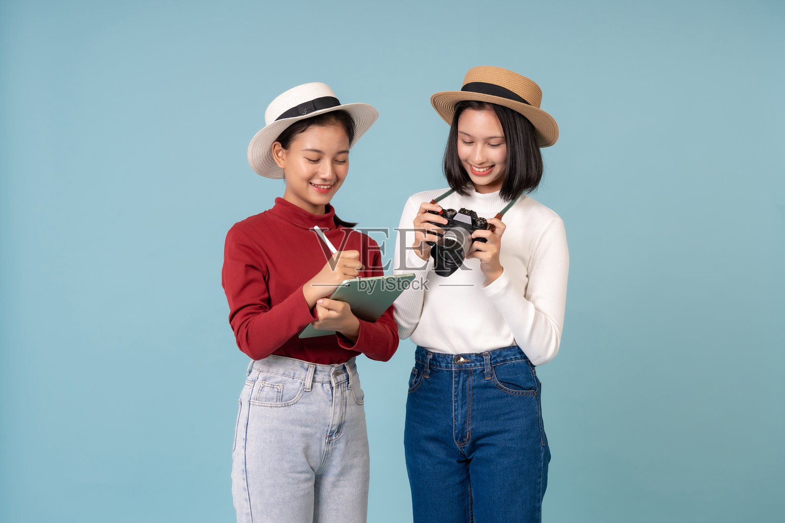 两位亚洲女学生一起旅行，携带着笔记本电脑和相机，穿着时尚休闲的服装，记录下旅行中的每一个难忘时刻。照片摄影图片