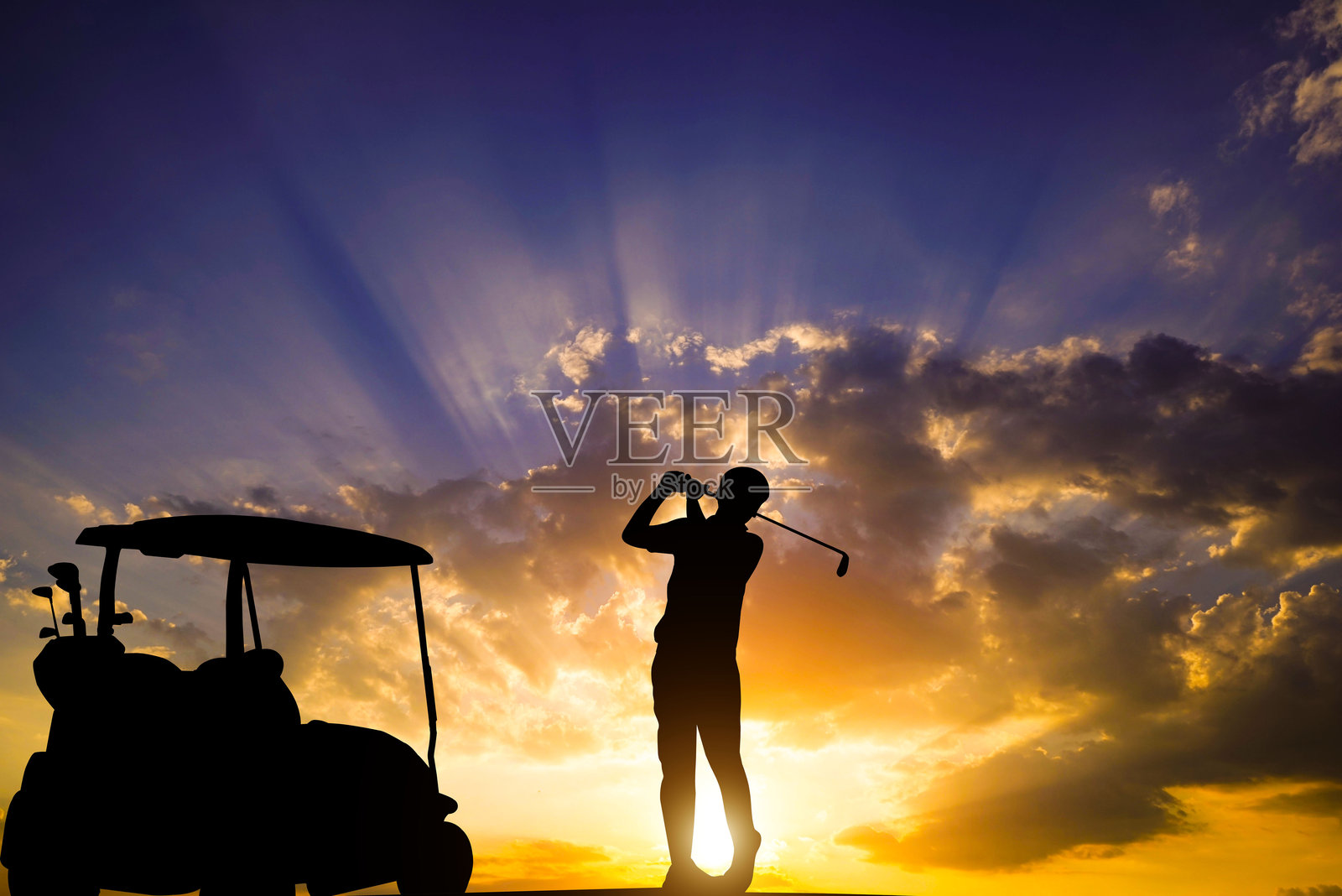 高尔夫球手在日落时分的剪影中击球向洞口。照片摄影图片