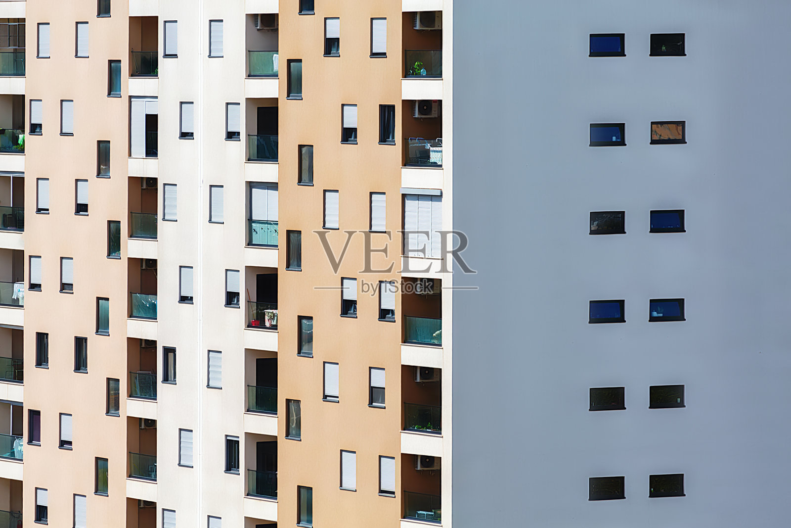现代公寓建筑外立面，具有对比鲜明的部分；一侧有阳台和窗户，另一侧则是极简风格的小窗户。照片摄影图片