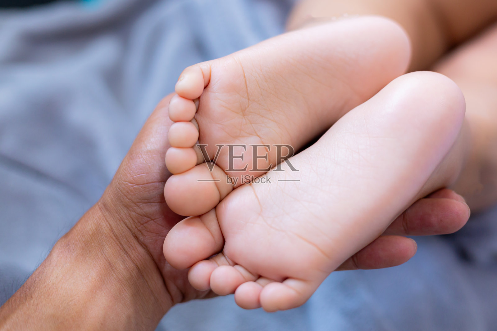 婴儿脚的特写，母亲手中的婴儿脚，婴儿脚的特写视角。母亲在小孩睡觉时轻触他的小脚趾。婴儿脚趾。新生儿特写摄影。迷人的小婴儿脚。照片摄影图片